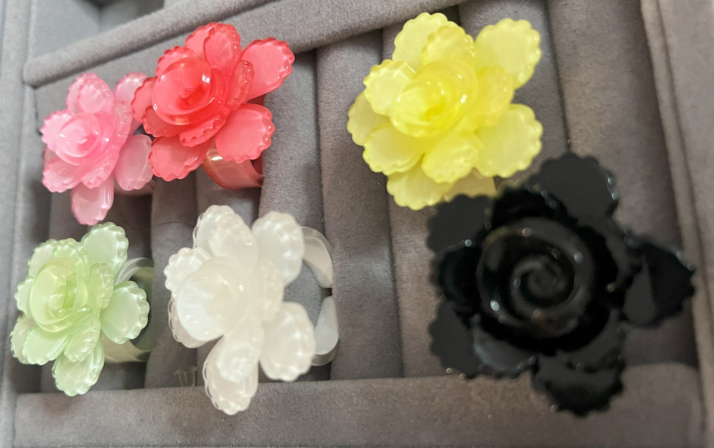 Anello Petalo di Primavera con fiore rosa tridimensionale in plastica colorata, disponibile in verde, rosa, rosso, giallo, bianco e nero, con petali scolpiti e finitura lucida
