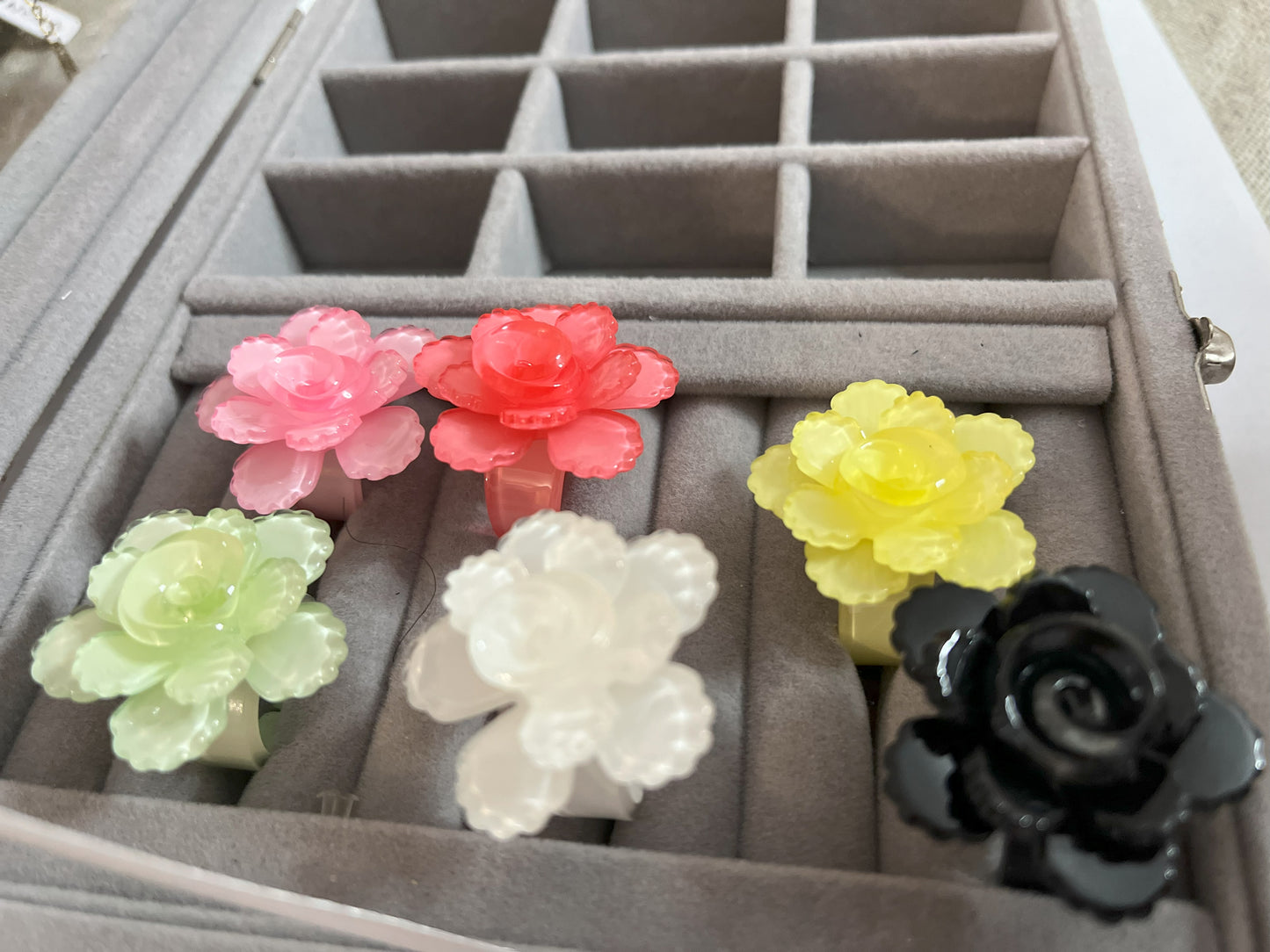 Anello Petalo di Primavera con fiore rosa tridimensionale in plastica colorata, disponibile in verde, rosa, rosso, giallo, bianco e nero, con petali scolpiti e finitura lucida