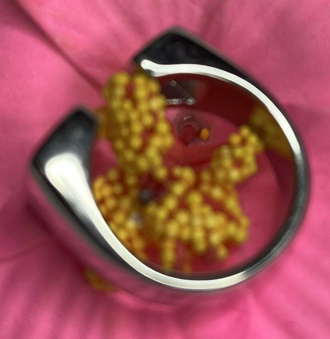 Anello Geometric Luxury con design geometrico quadrato, disponibile in versione placcata oro e argento, esposto su fiore rosa decorativo