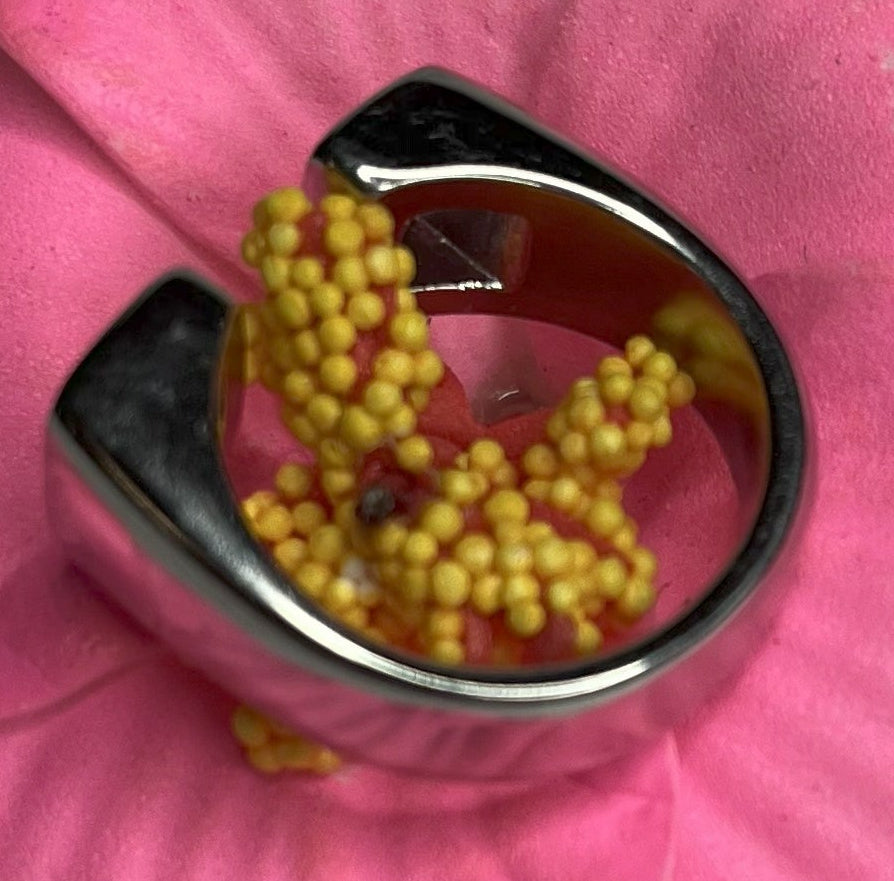 Anello Geometric Luxury con design geometrico quadrato, disponibile in versione placcata oro e argento, esposto su fiore rosa decorativo