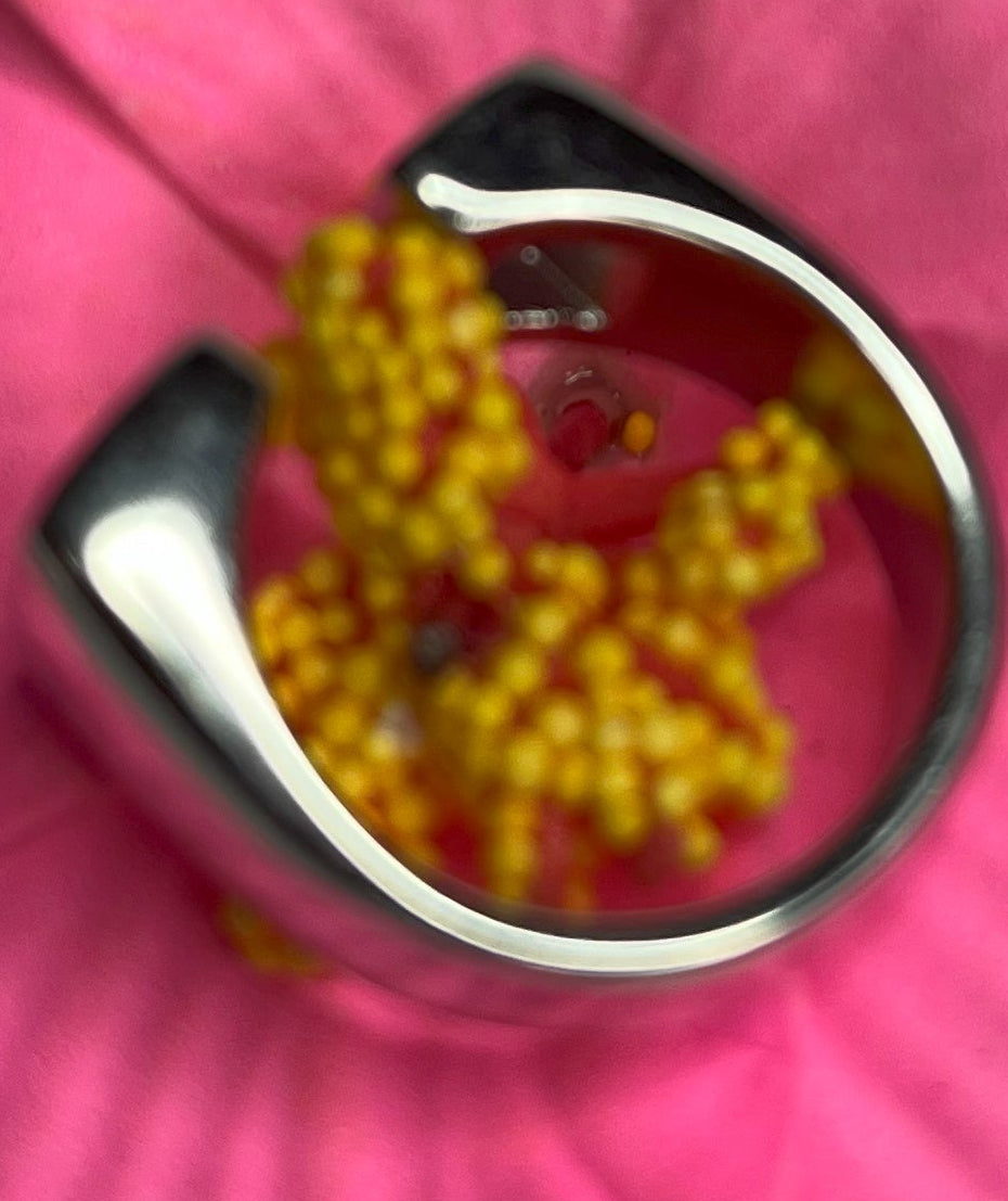 Anello Geometric Luxury con design geometrico quadrato, disponibile in versione placcata oro e argento, esposto su fiore rosa decorativo