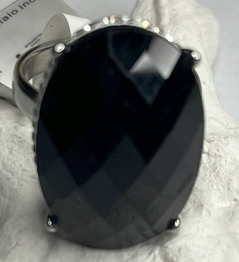 Anello con pietra nera ovale lucida e montatura argentata o dorata decorata, appoggiato su stella marina bianca