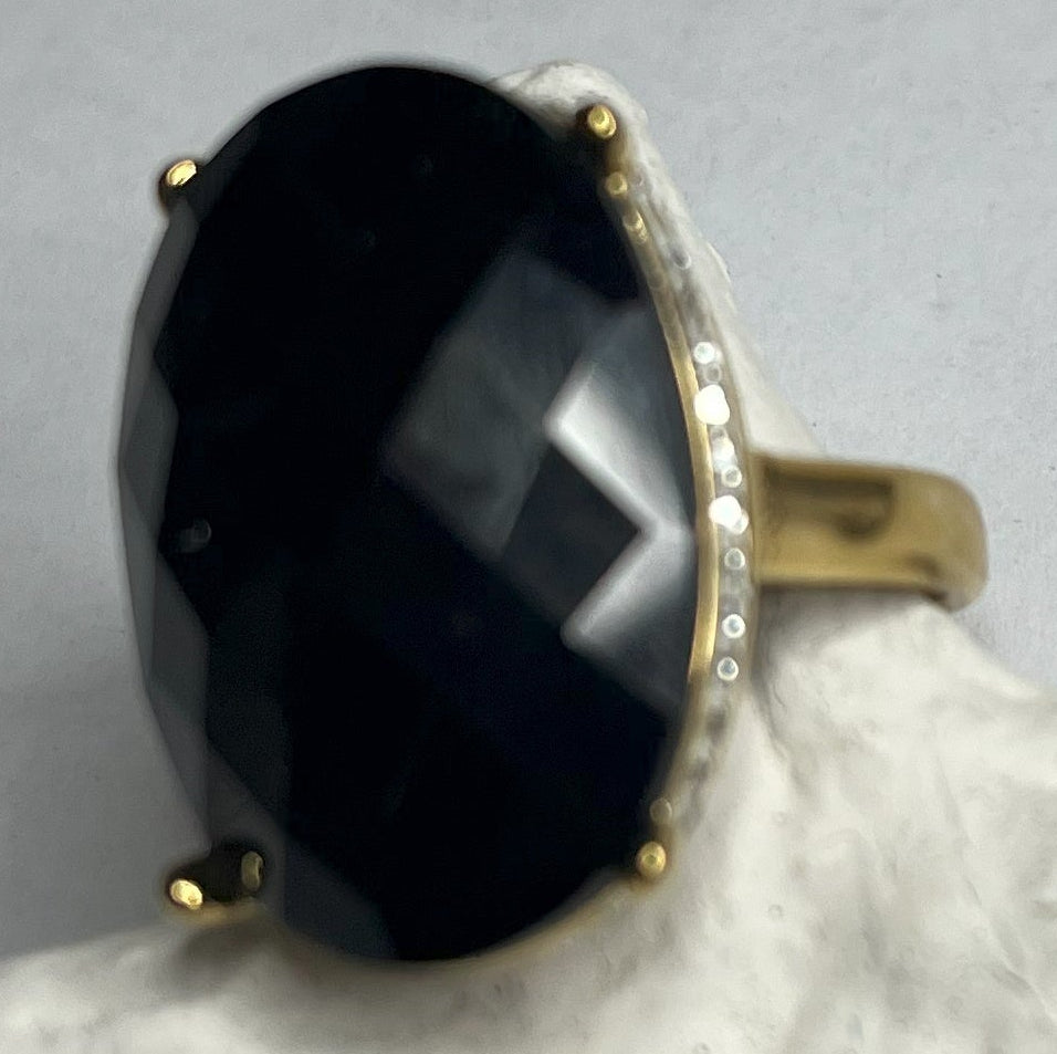 Anello con pietra nera ovale lucida e montatura argentata o dorata decorata, appoggiato su stella marina bianca