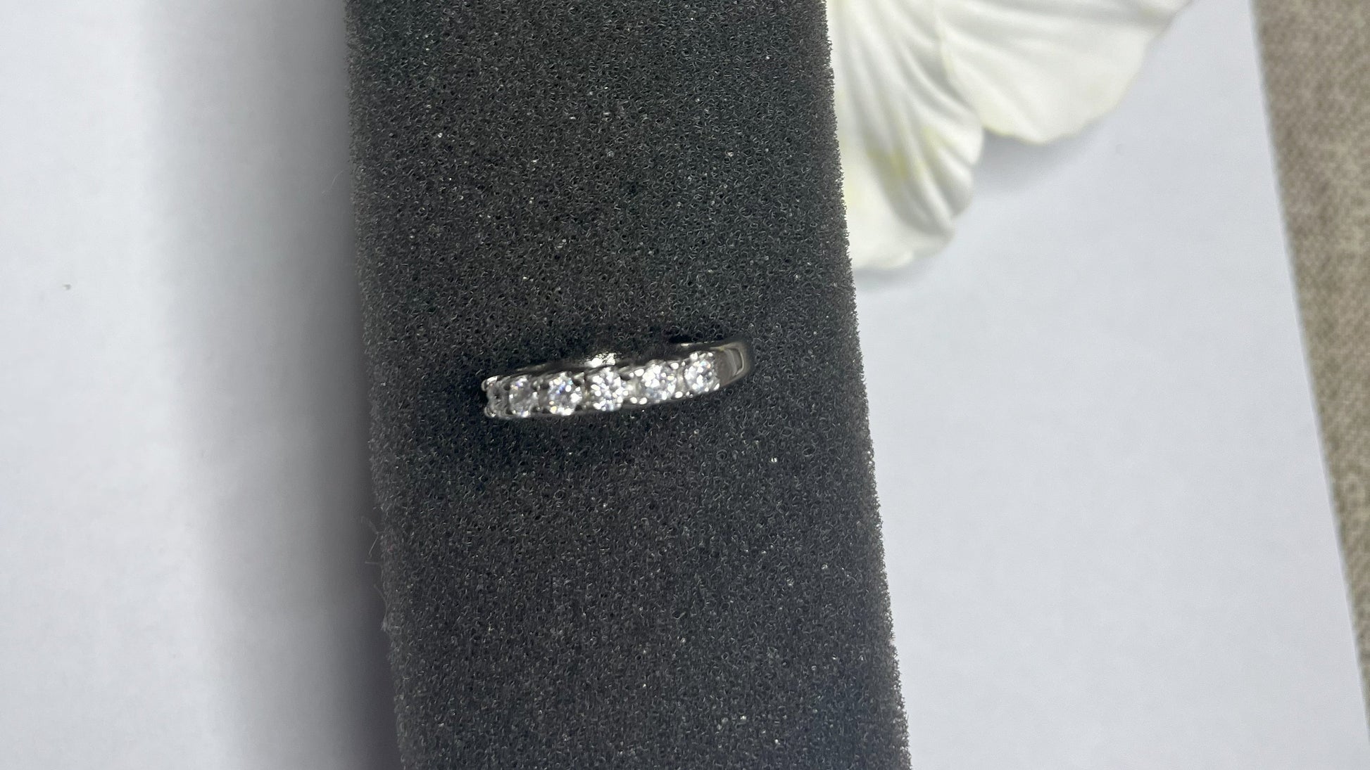 Anello Quintessenza d'Amore con cinque diamanti brillanti incastonati in acciaio di alta qualità placcato argento, fotografato su sfondo nero vellutato