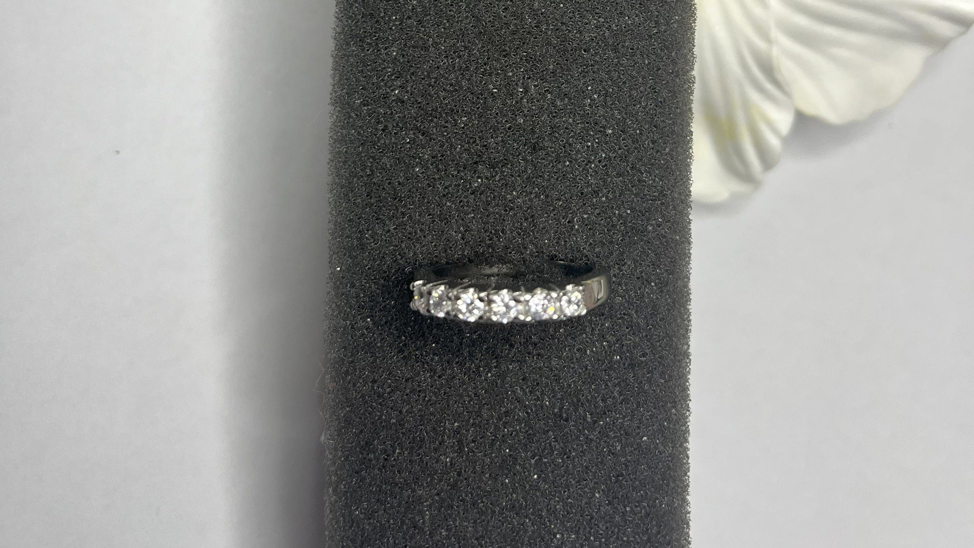 Anello Quintessenza d'Amore con cinque diamanti brillanti incastonati in acciaio di alta qualità placcato argento, fotografato su sfondo nero vellutato