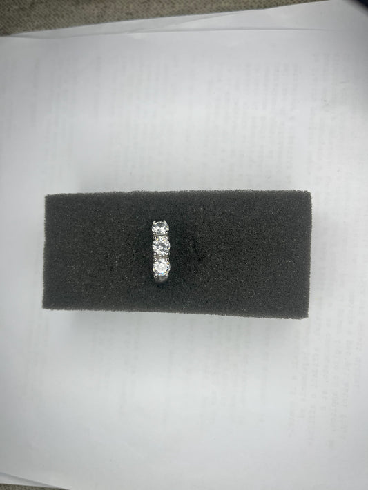 Anello Trio in acciaio premium placcato argento con tre zirconi brillanti perfettamente incastonati, fotografato su superficie scura che esalta la brillantezza delle pietre