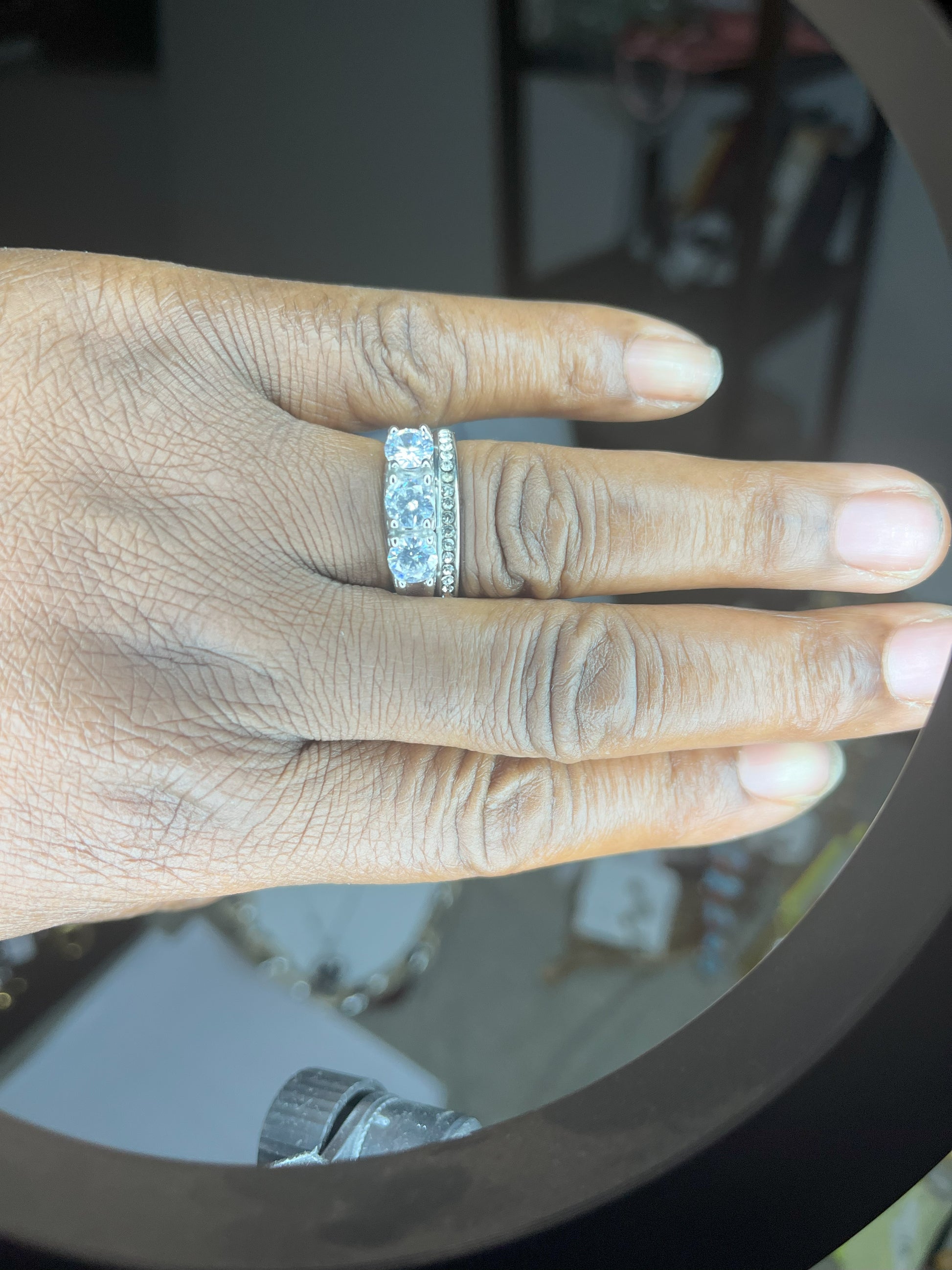 Anello Trio in acciaio premium placcato argento con tre zirconi brillanti perfettamente incastonati, fotografato su mano femminile