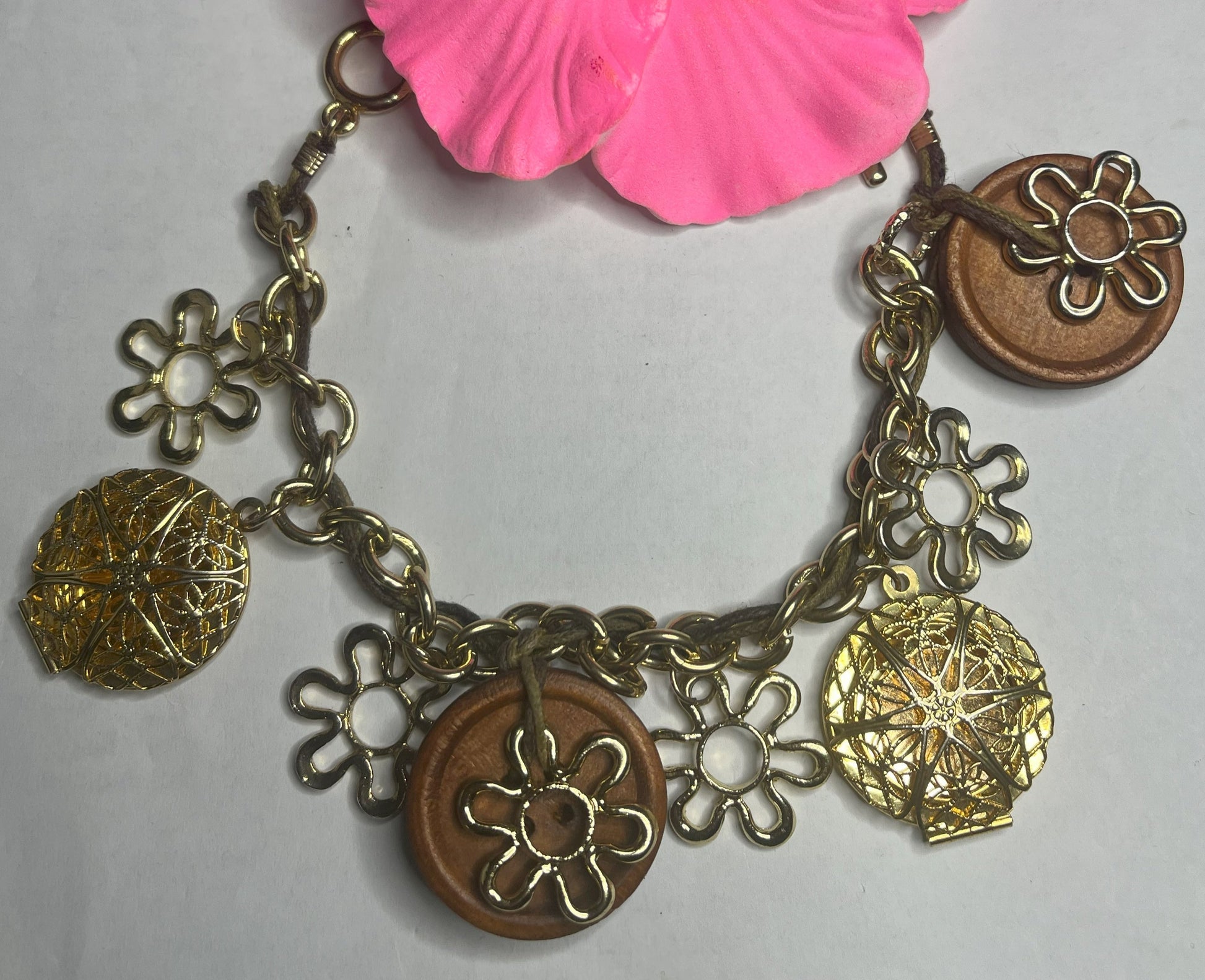 Bracciale Charm Fiori Vintage dorato con ciondoli floreali e hibiscus rosa, lavorazione artigianale italiana su sfondo neutro