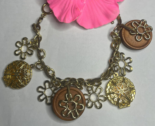 Bracciale Charm Fiori Vintage dorato con ciondoli floreali e hibiscus rosa, lavorazione artigianale italiana su sfondo neutro