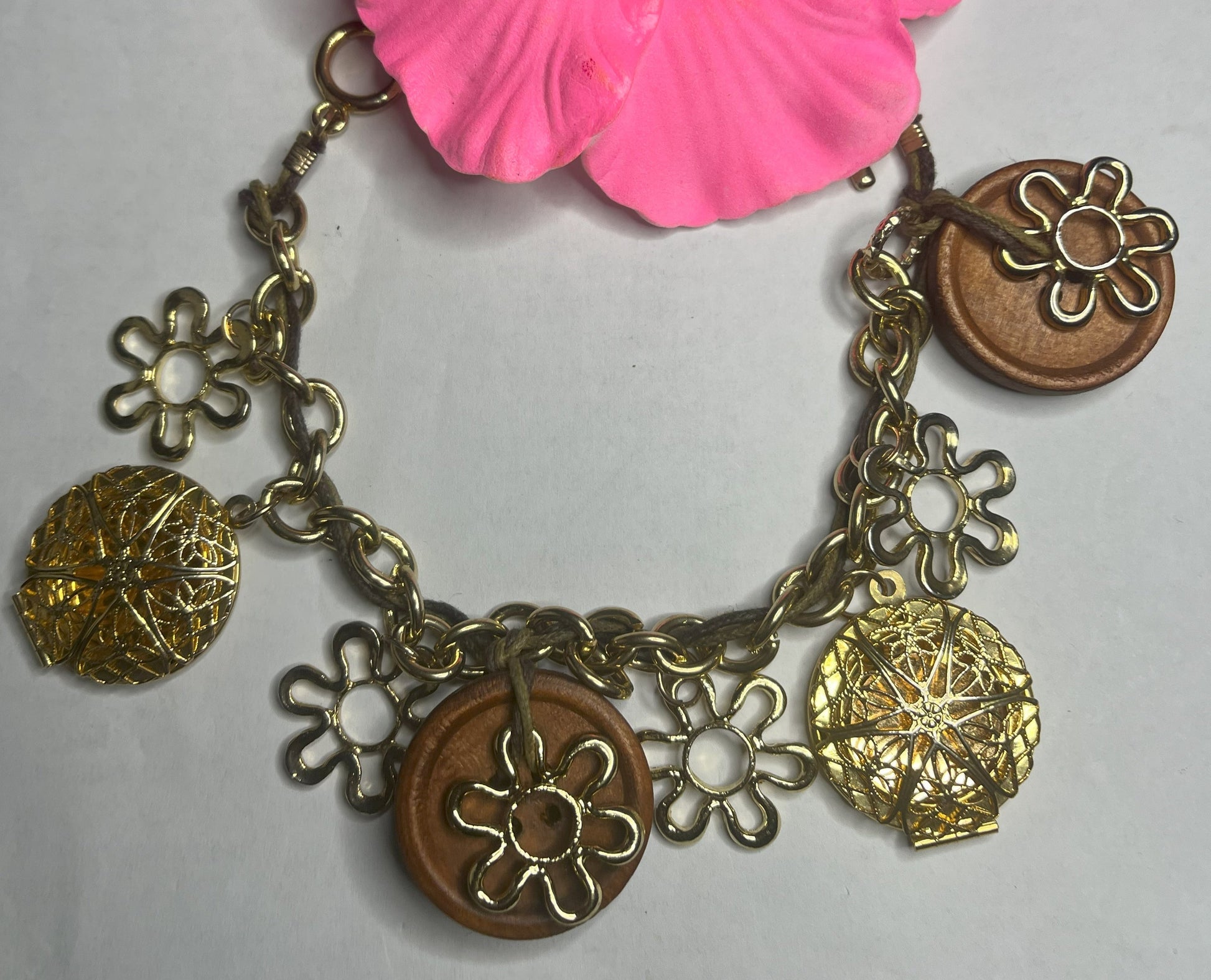 Bracciale Charm Fiori Vintage dorato con ciondoli floreali e hibiscus rosa, lavorazione artigianale italiana su sfondo neutro