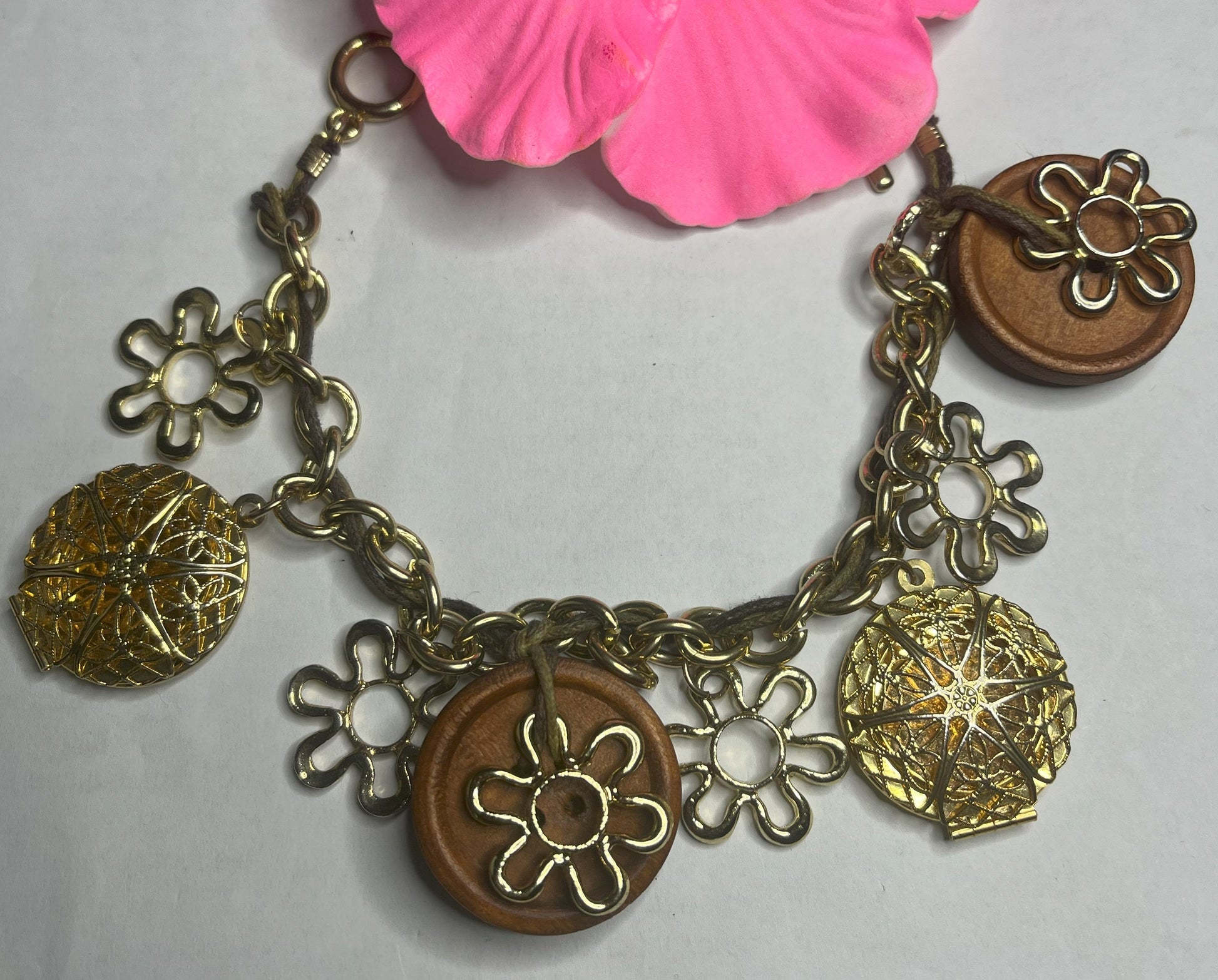 Bracciale Charm Fiori Vintage dorato con ciondoli floreali e hibiscus rosa, lavorazione artigianale italiana su sfondo neutro