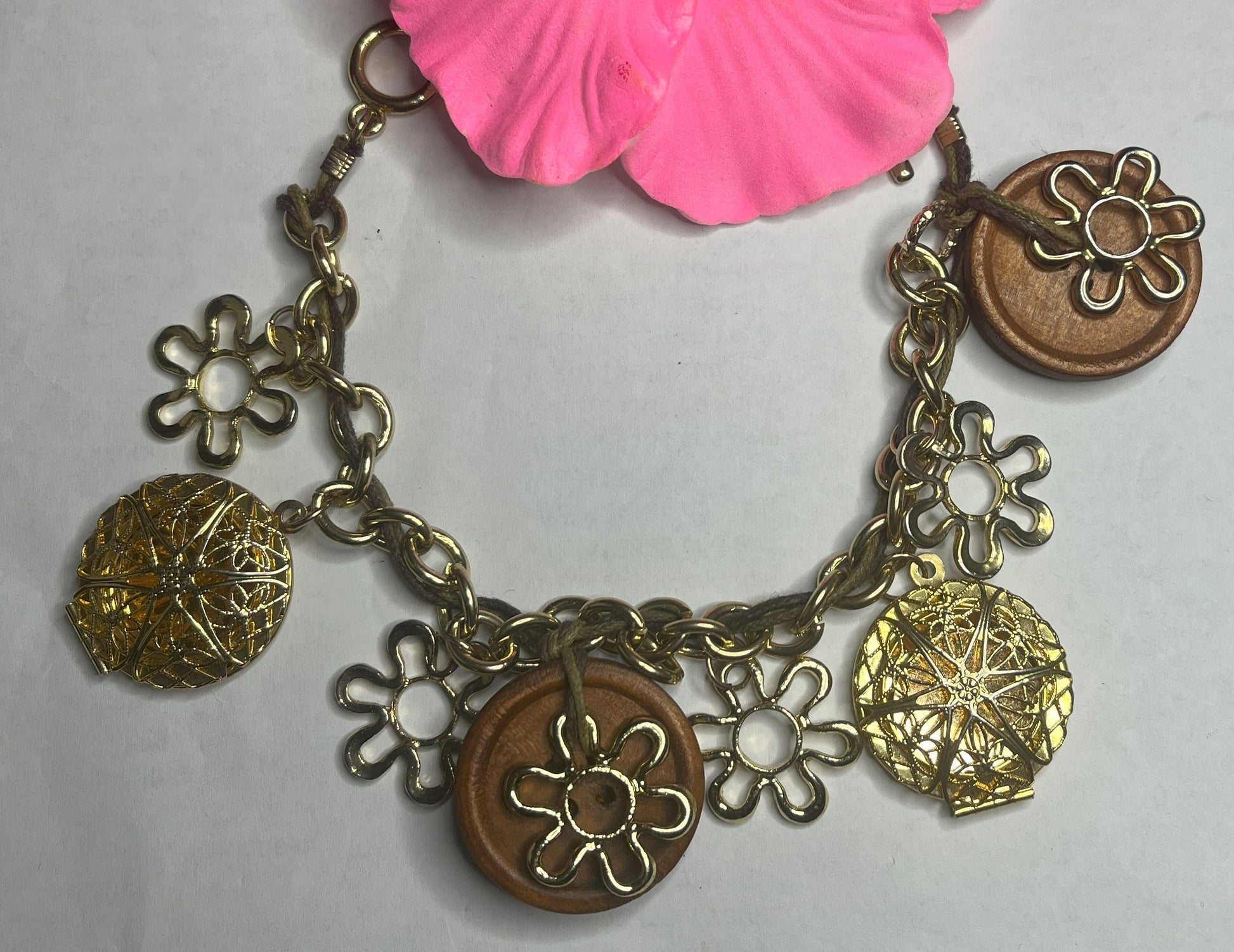 Bracciale Charm Fiori Vintage dorato con ciondoli floreali e hibiscus rosa, lavorazione artigianale italiana su sfondo neutro