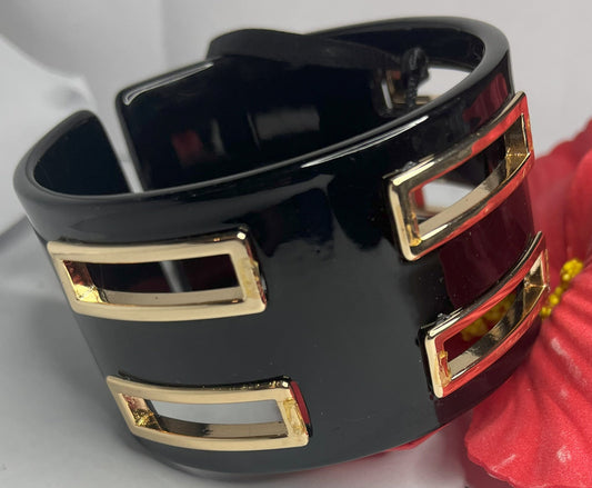 Bracciale rigido Golden Fusion nero con inserti geometrici placcati oro, design moderno ed elegante su sfondo bianco