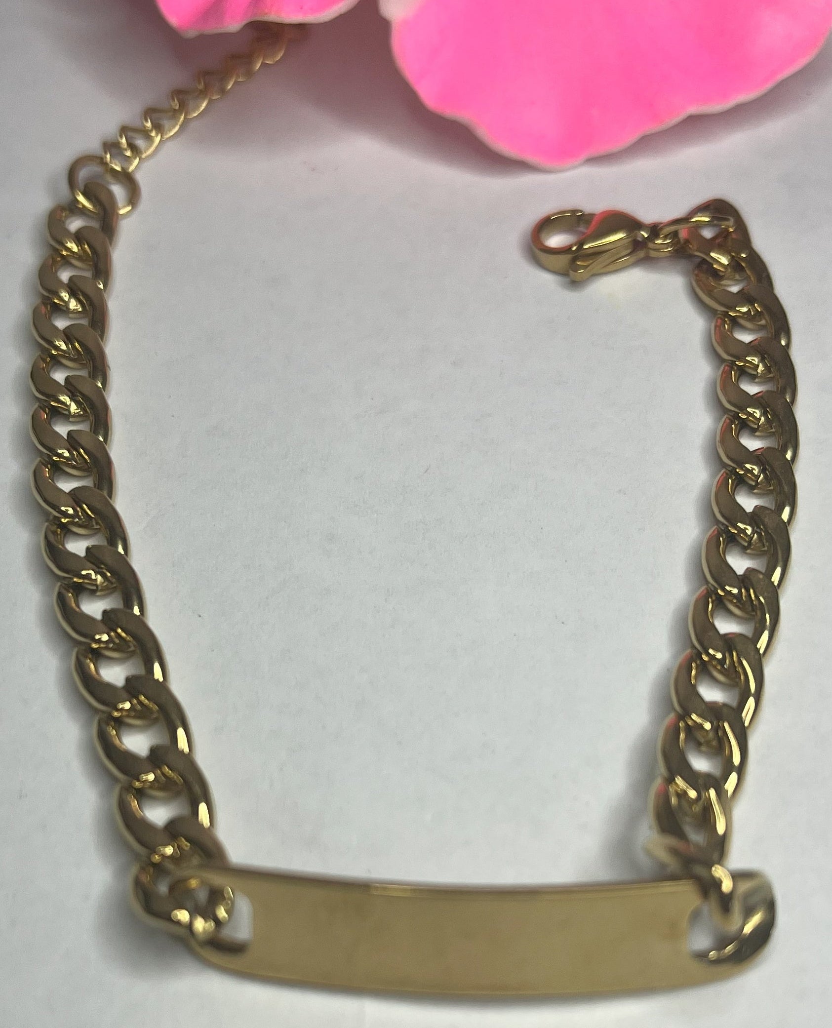 Bracciale Golden Thread sottile placcato oro con maglia fine delicata su sfondo grigio con petali rosa