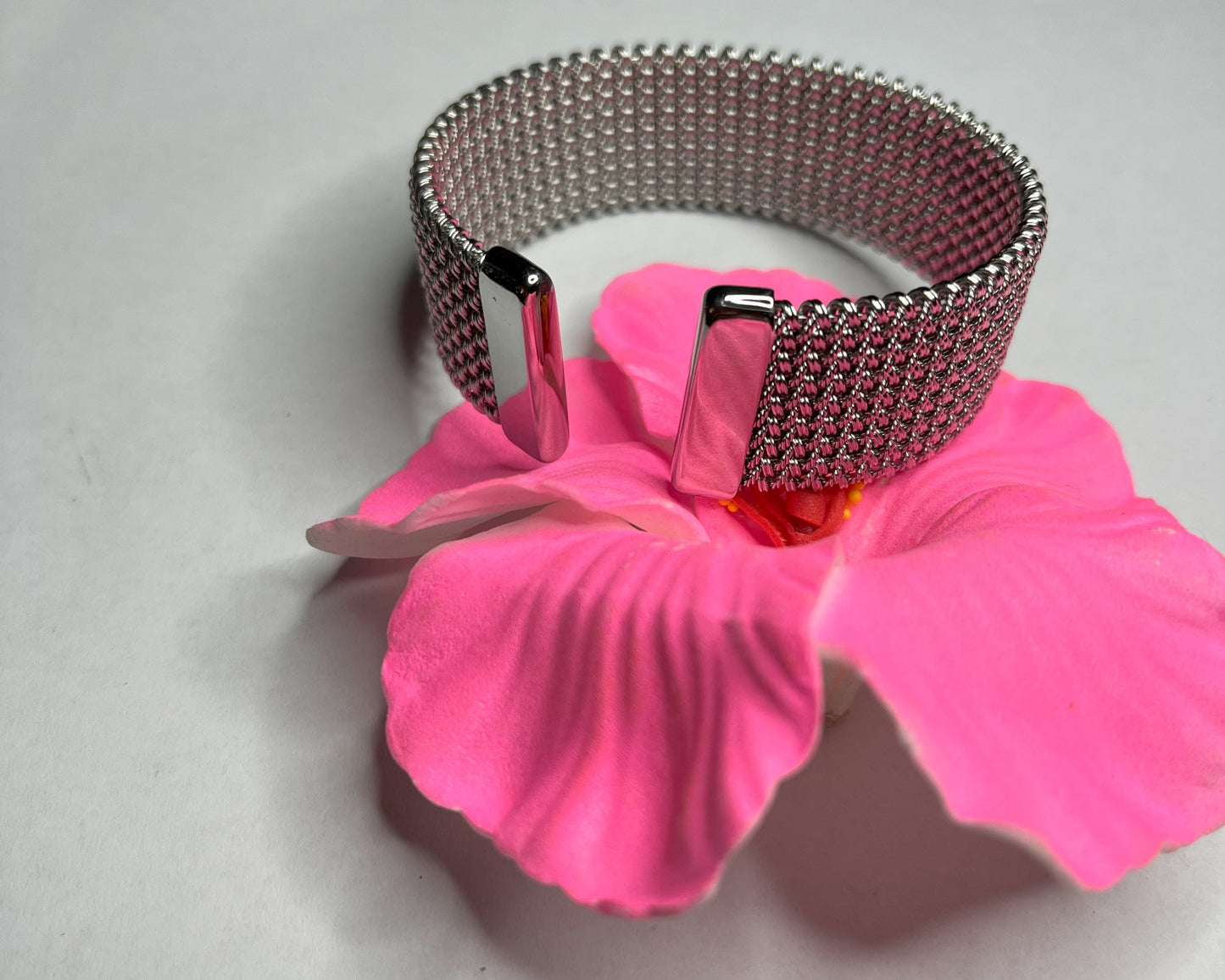 Braccialetto Cocò-G con elegante maglia dorata mesh e chiusura magnetica, esposto su piatto bianco con decorazioni floreali rosa
