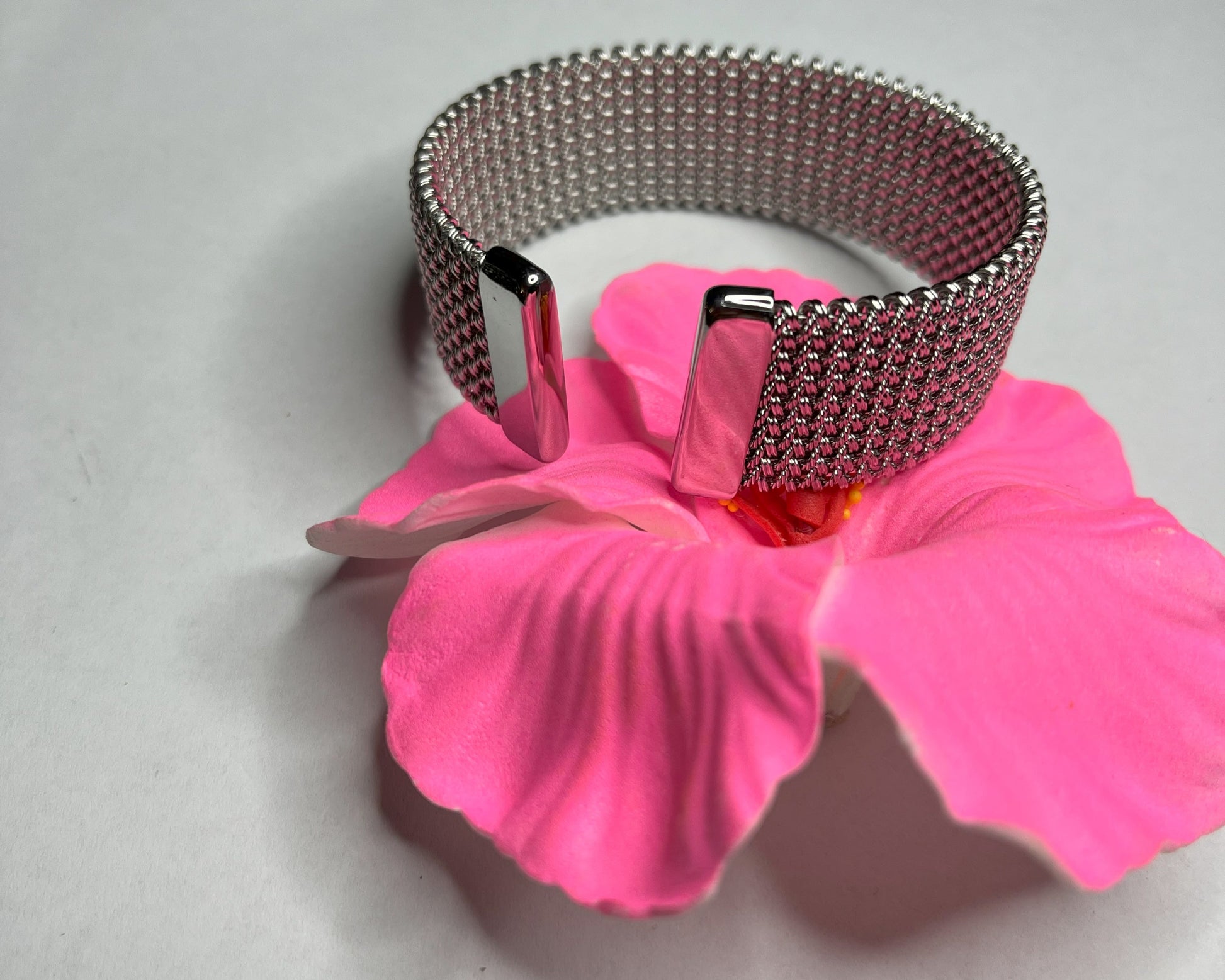 Braccialetto Cocò-G con elegante maglia dorata mesh e chiusura magnetica, esposto su piatto bianco con decorazioni floreali rosa