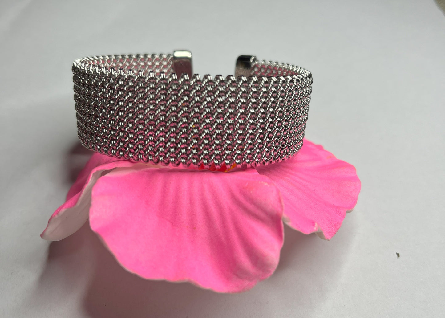 Braccialetto Cocò-G con elegante maglia argentata mesh e chiusura magnetica, esposto su fiore rosa