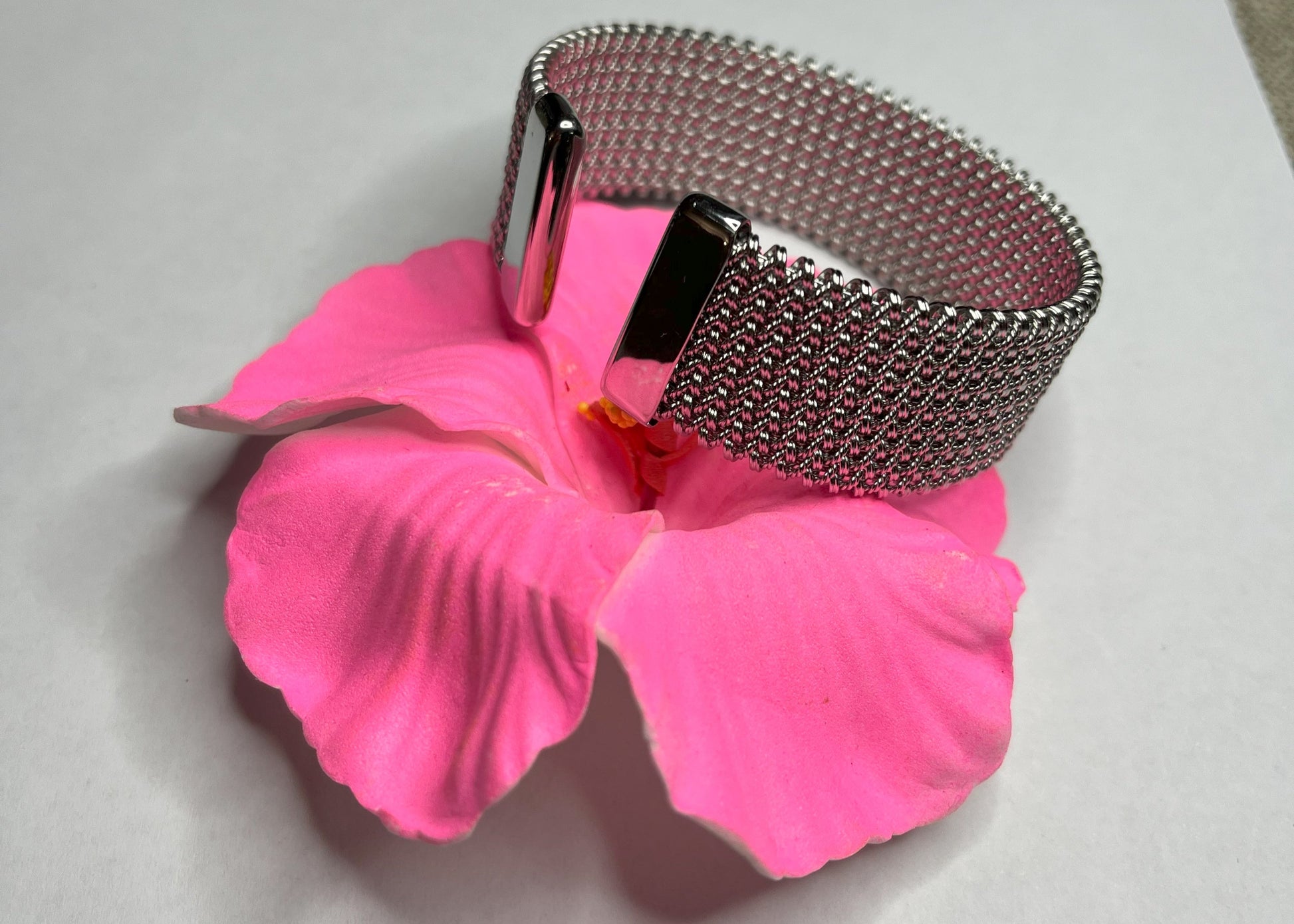 Braccialetto Cocò-G con elegante maglia dorata mesh e chiusura magnetica, esposto su piatto bianco con decorazioni floreali rosa