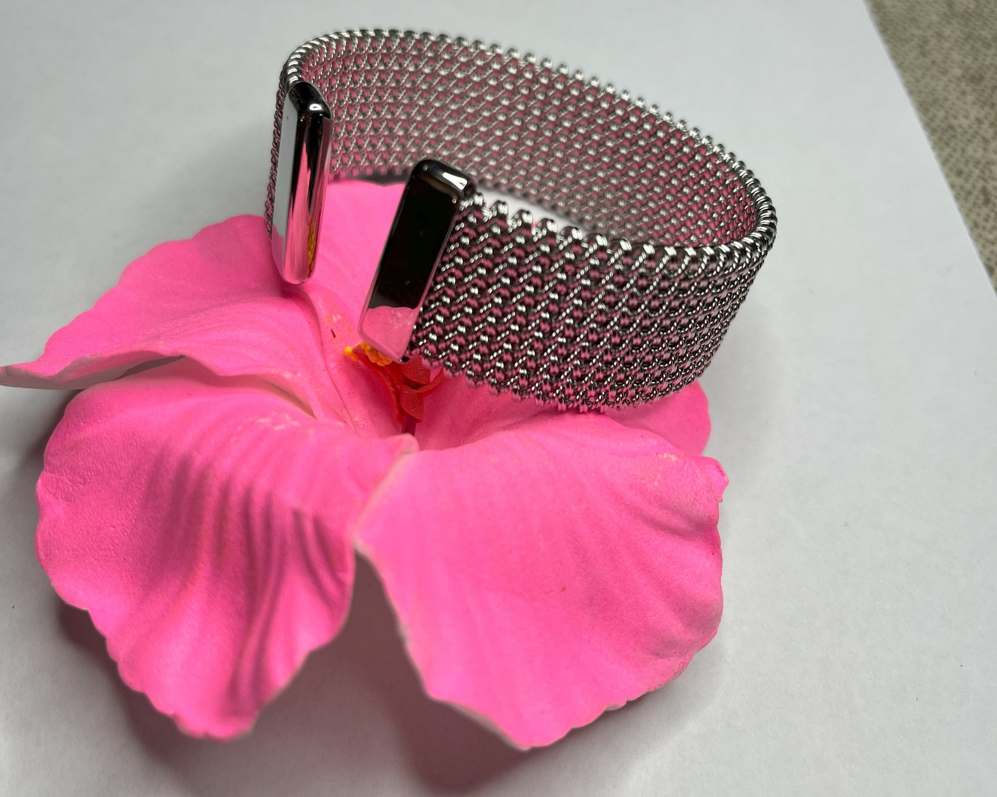 Braccialetto Cocò-G con elegante maglia dorata mesh e chiusura magnetica, esposto su piatto bianco con decorazioni floreali rosa