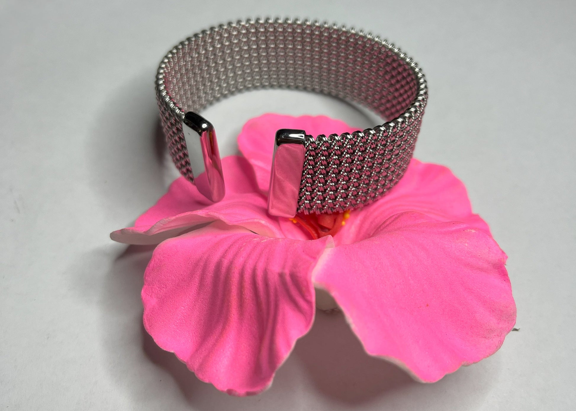 Braccialetto Cocò-G con elegante maglia dorata mesh e chiusura magnetica, esposto su piatto bianco con decorazioni floreali rosa