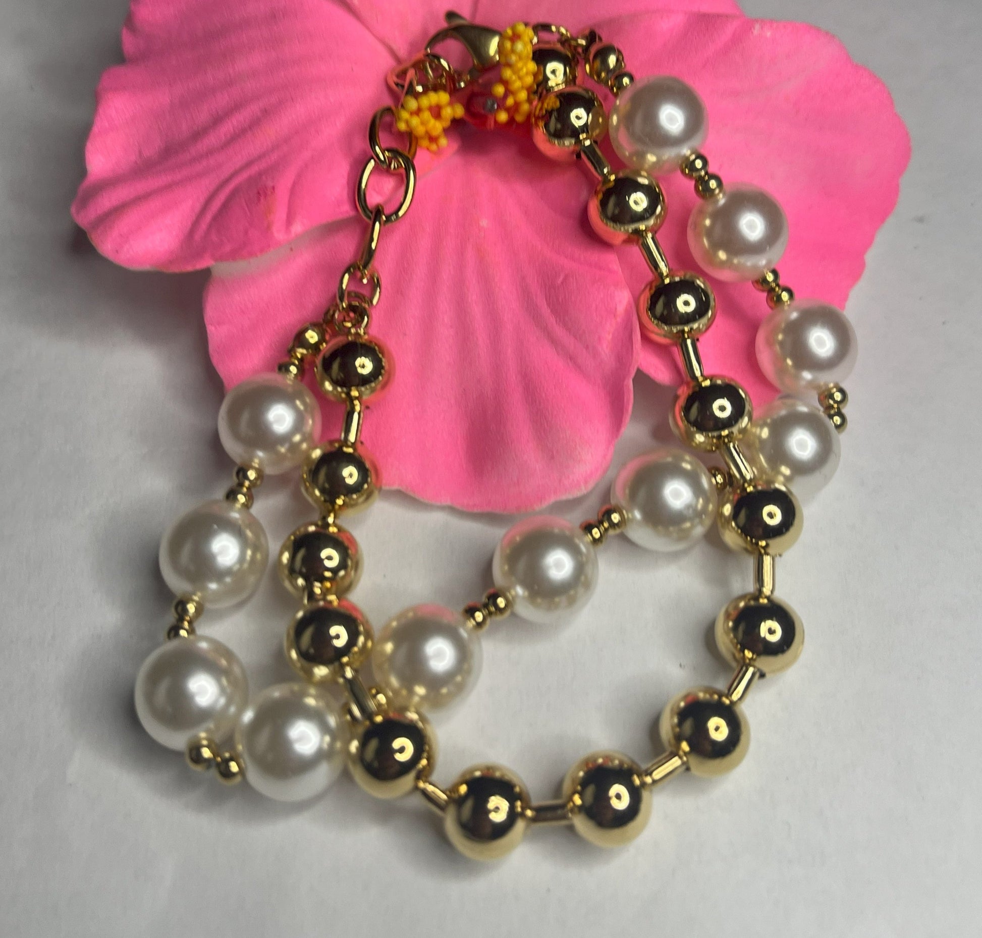Braccialetto doppio eleganza dorata con sfere color oro e perlato su petali rosa