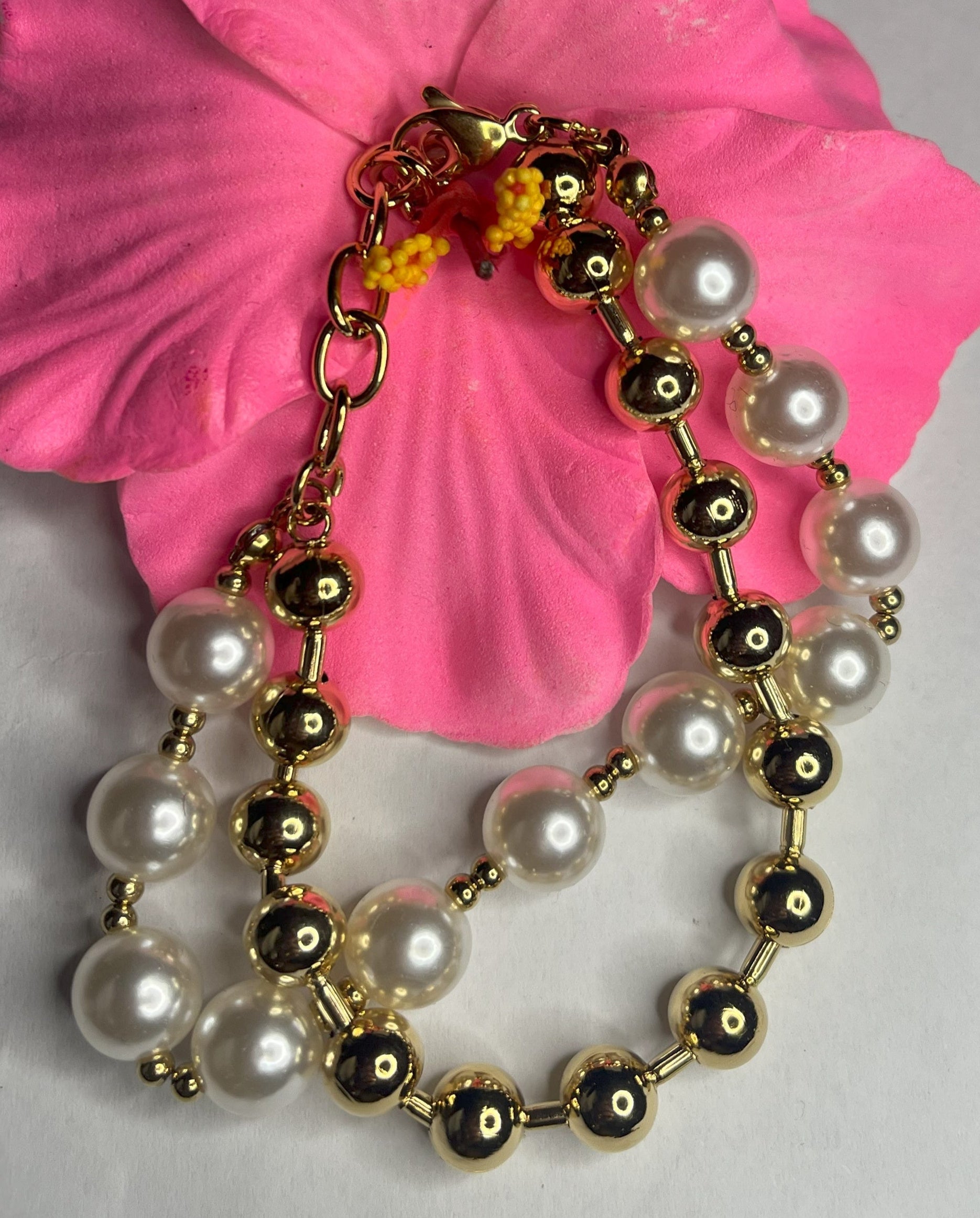 Braccialetto doppio eleganza dorata con sfere color oro e perlato su petali rosa