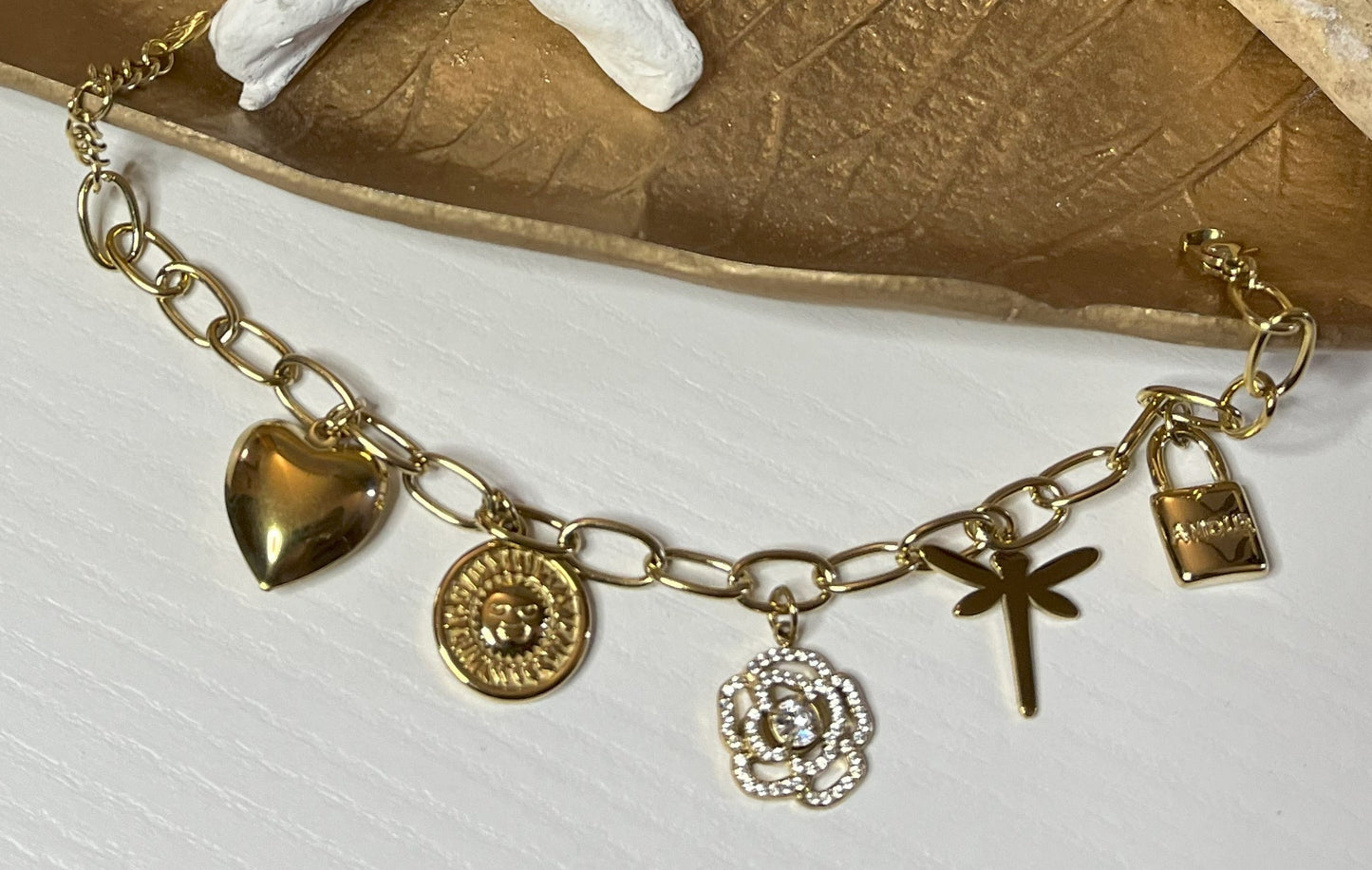 Braccialetto Multi-Charm in oro con ciondoli eleganti su sfondo neutro