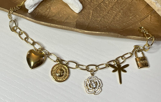 Braccialetto Multi-Charm in oro con ciondoli eleganti su sfondo neutro