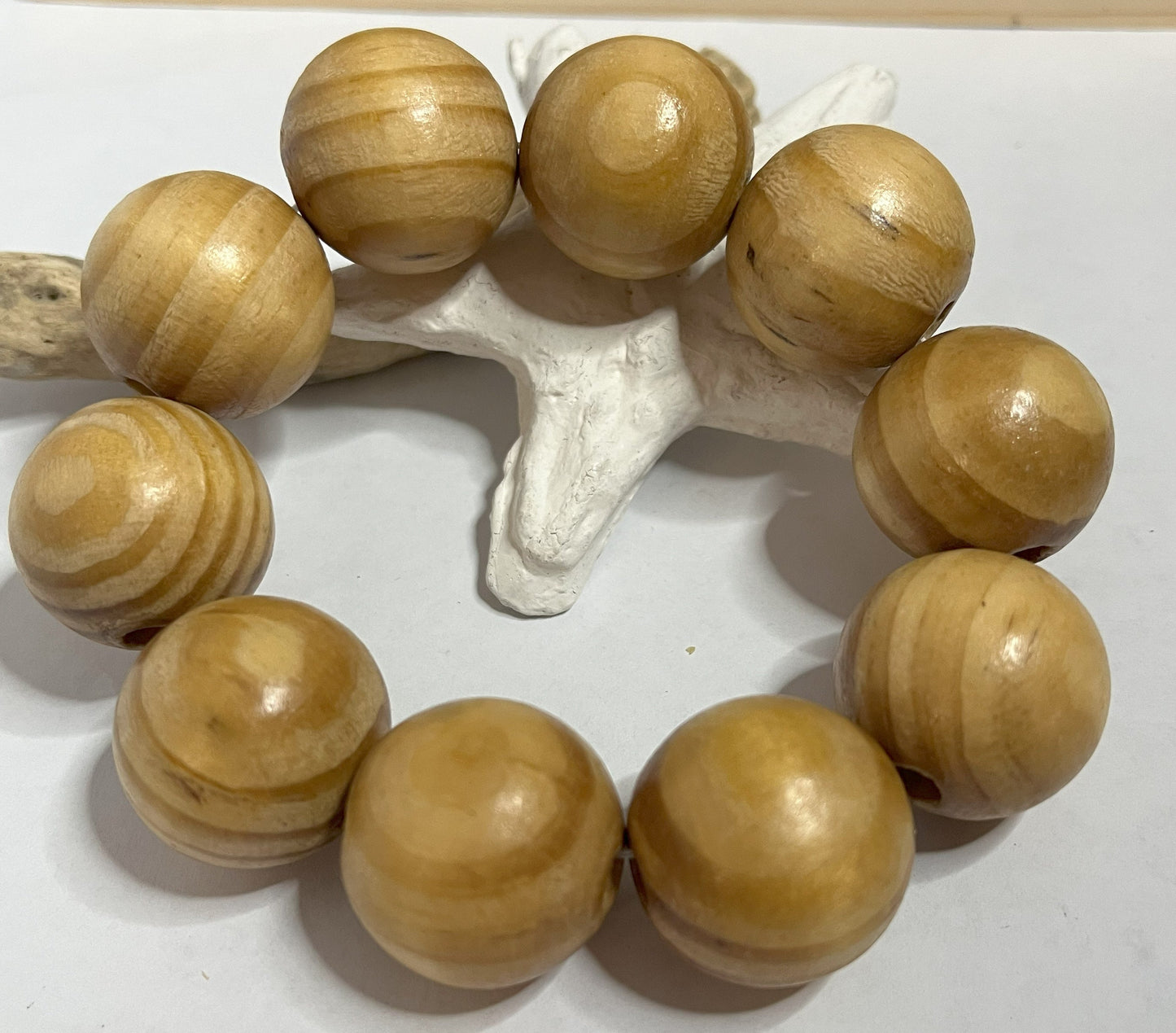Braccialetto con sfere di legno dall'effetto twist spirale, disposto su sfondo bianco con decorazione marina