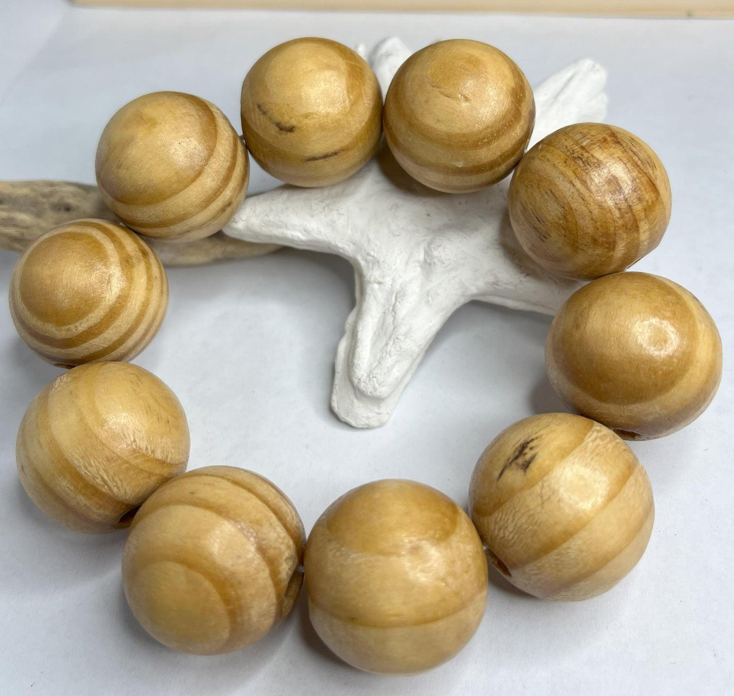 Braccialetto con sfere di legno dall'effetto twist spirale, disposto su sfondo bianco con decorazione marina