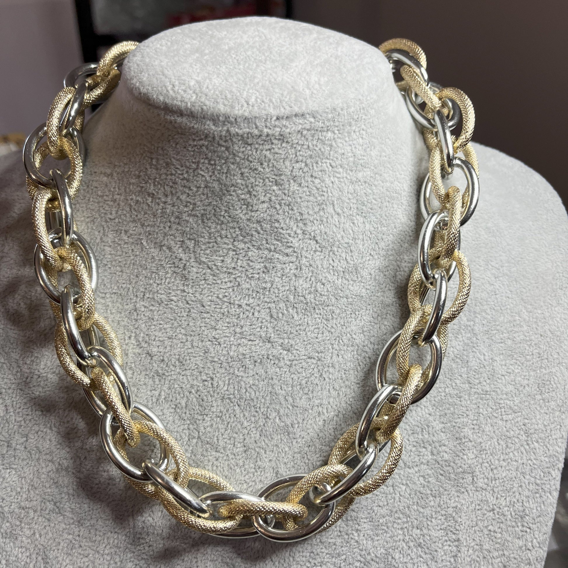 Collana Catena Eclipse in alluminio premium con anelli texturizzati dorati su busto espositore, design moderno con effetti luce-ombra