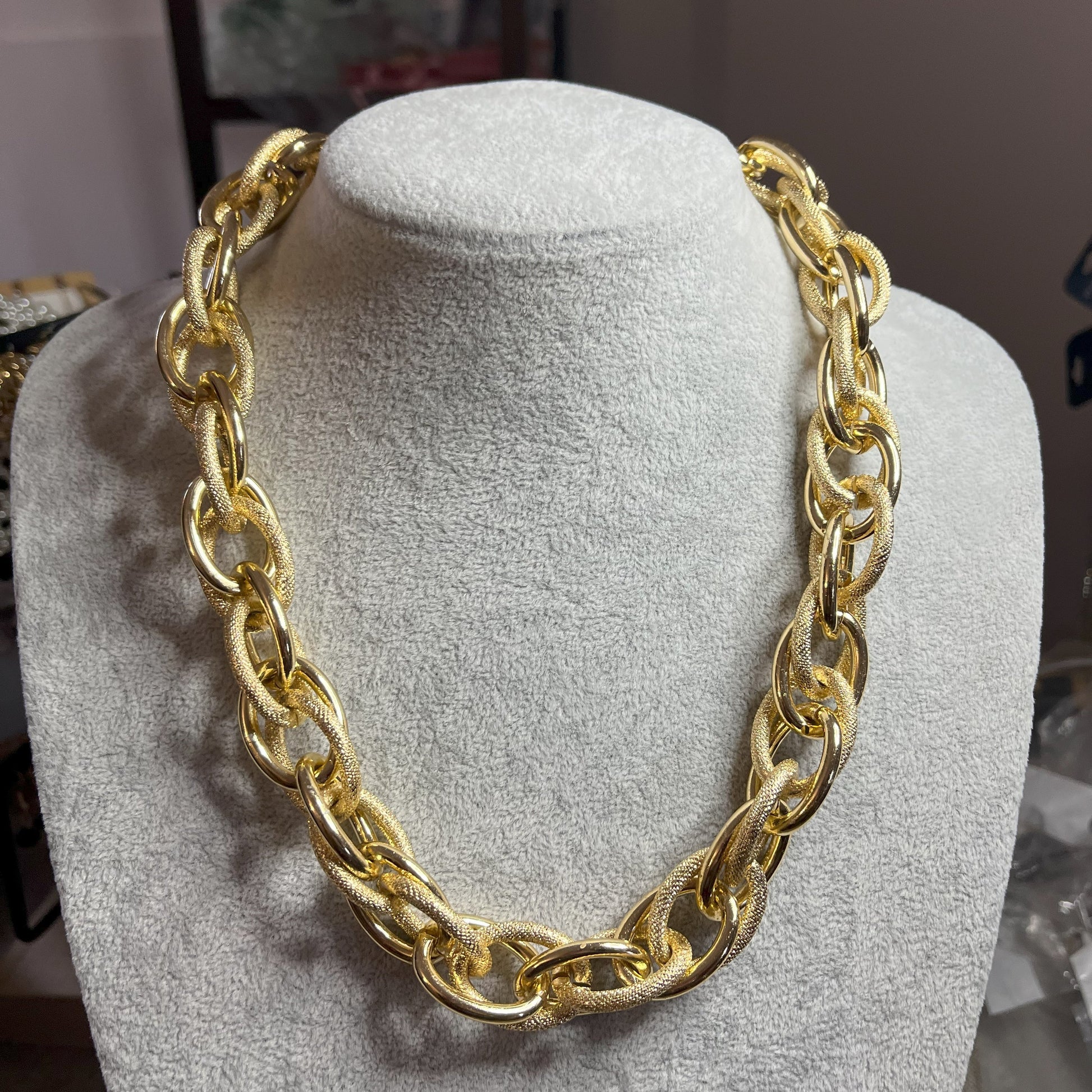 Collana Catena Eclipse in alluminio premium con anelli texturizzati dorati su busto espositore, design moderno con effetti luce-ombra