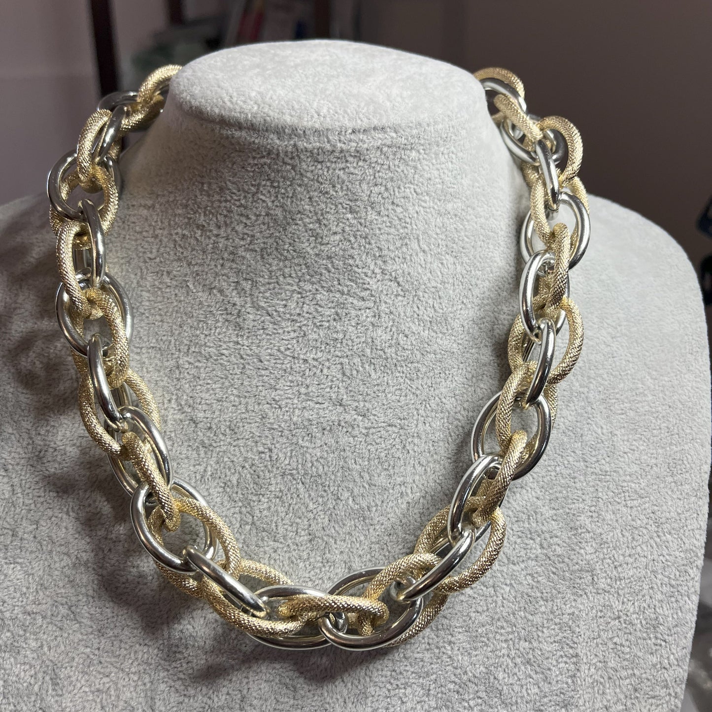 Collana Catena Eclipse in alluminio premium con anelli texturizzati dorati su busto espositore, design moderno con effetti luce-ombra