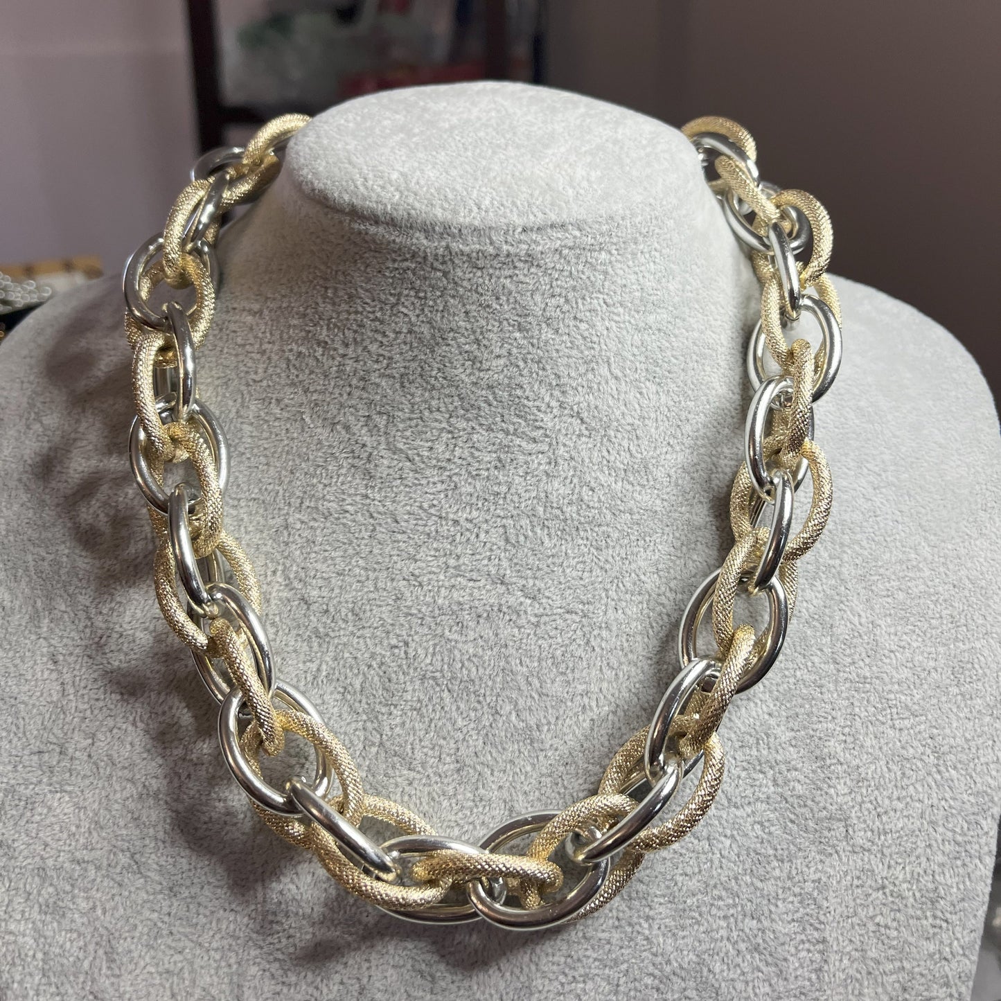 Collana Catena Eclipse in alluminio premium con anelli texturizzati dorati su busto espositore, design moderno con effetti luce-ombra