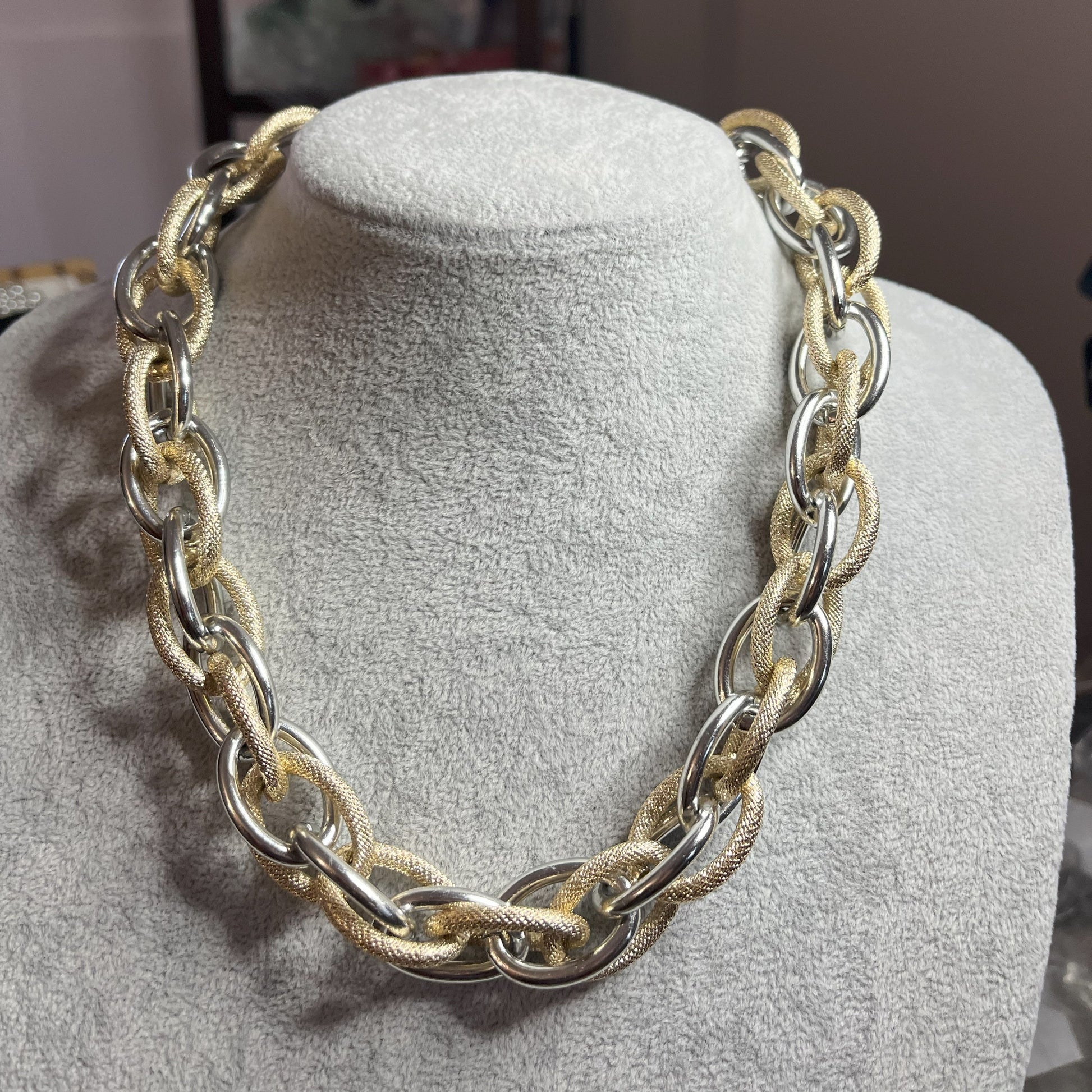 Collana Catena Eclipse in alluminio premium con anelli texturizzati dorati su busto espositore, design moderno con effetti luce-ombra