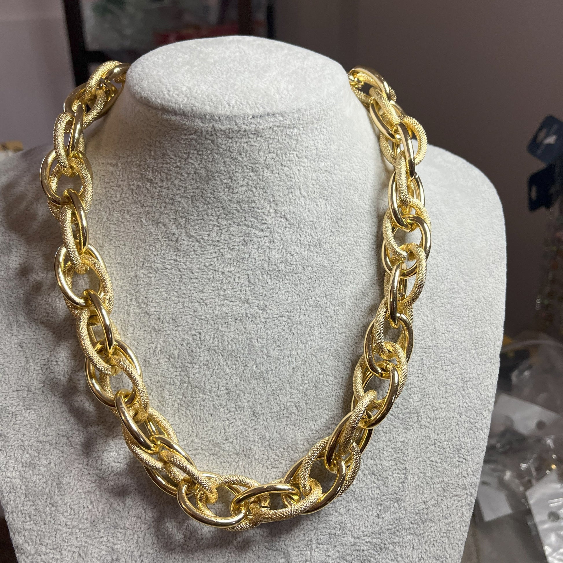 Collana Catena Eclipse in alluminio premium con anelli texturizzati dorati su busto espositore, design moderno con effetti luce-ombra