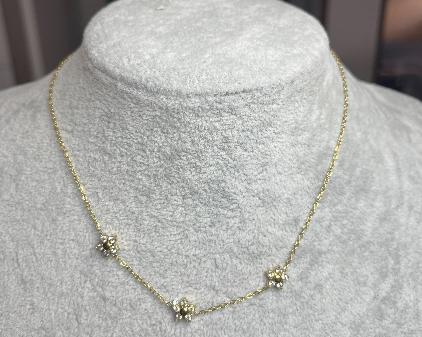 Collana 3 Margherite Dorate - elegante catena dorata con tre margherite brillanti, gioiello floreale su busto espositore