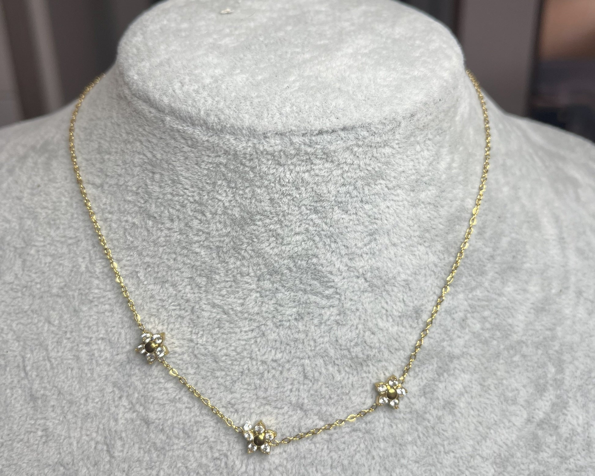Collana 3 Margherite Dorate - elegante catena dorata con tre margherite brillanti, gioiello floreale su busto espositore