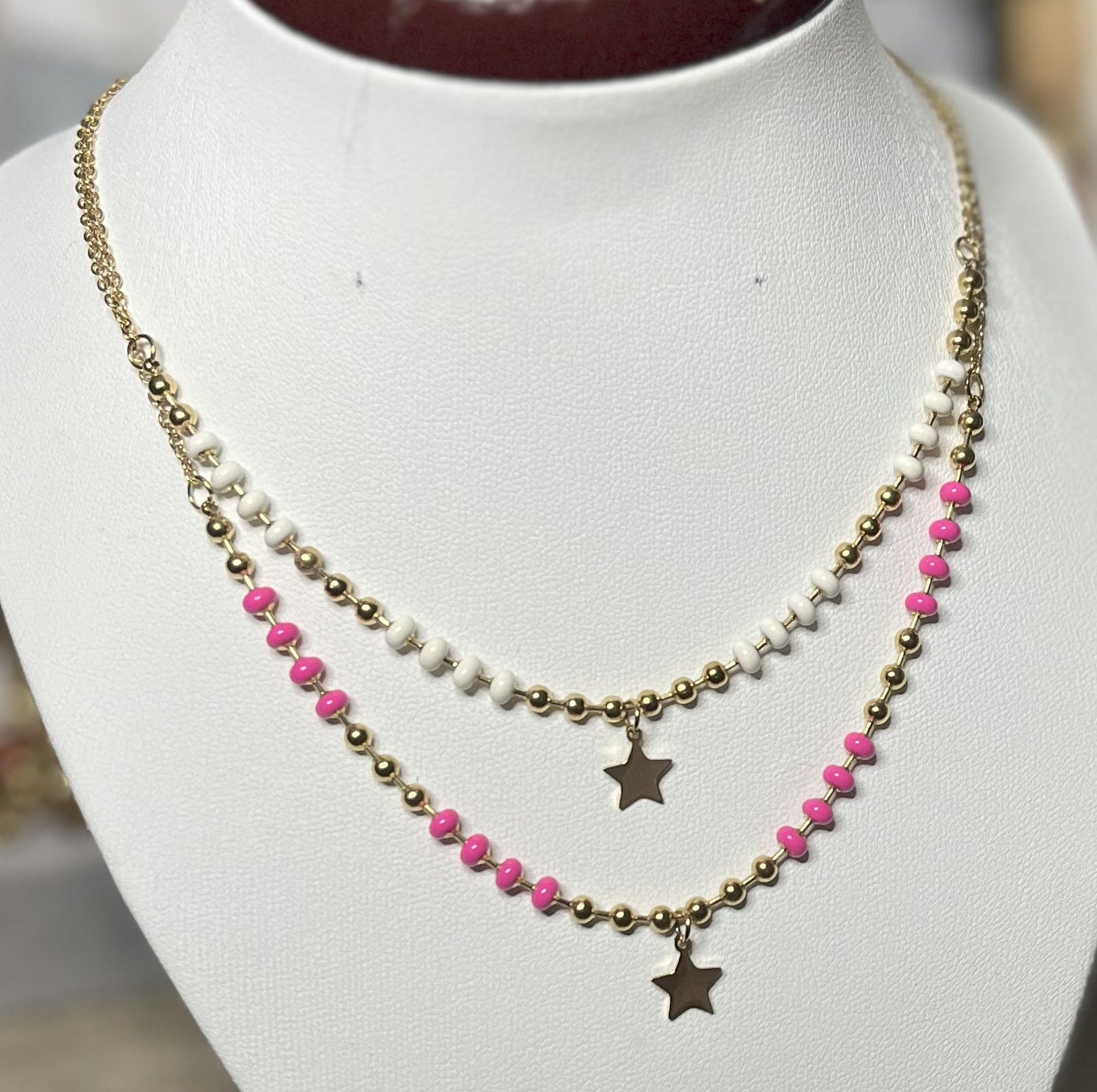 Collana in acciaio inossidabile con perline colorate e ciondolo stella dorata, esposta su busto per gioielli