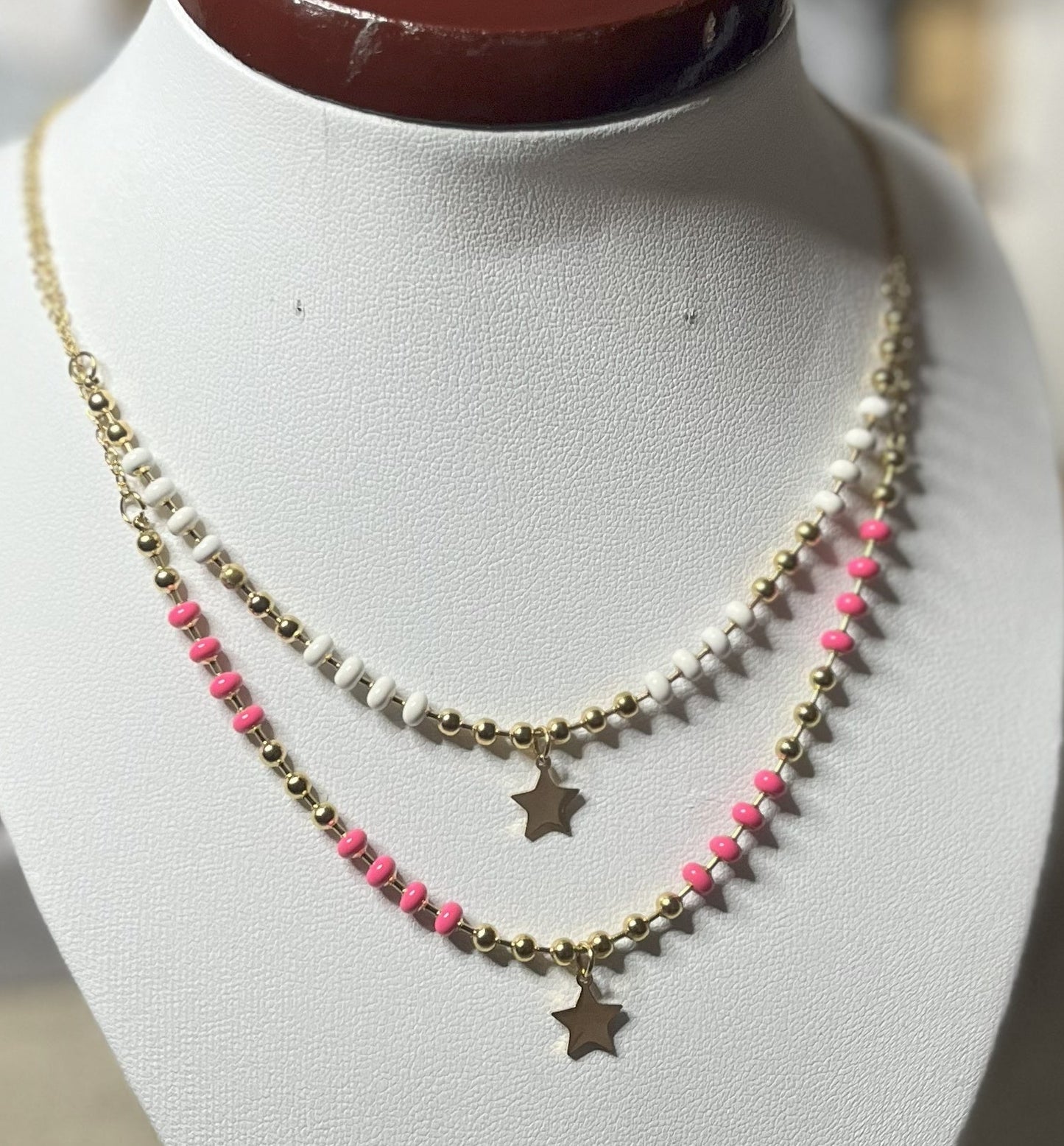 Collana in acciaio inossidabile con perline colorate e ciondolo stella dorata, esposta su busto per gioielli