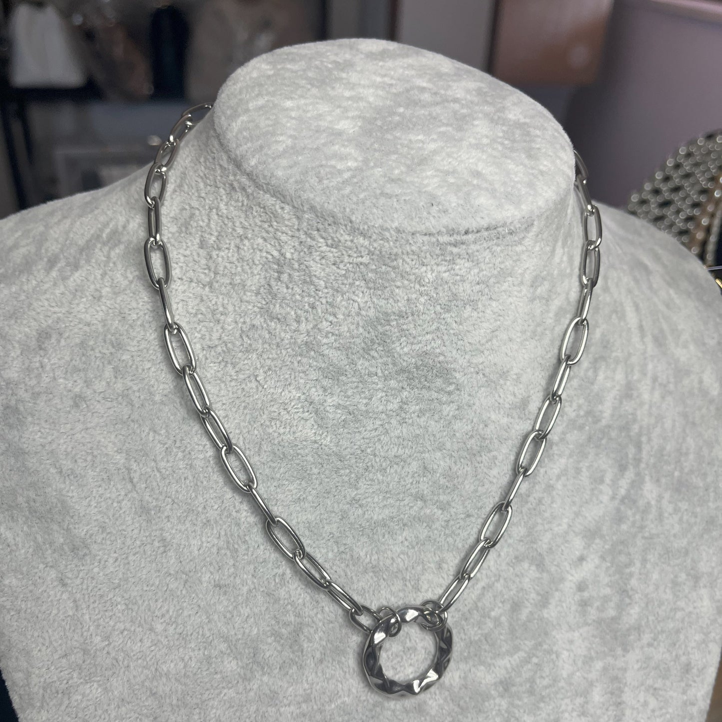 Collana Catena Cerchio in acciaio inox placcato argento con catena a maglie ovali e ciondolo cerchio, esposta su busto grigio