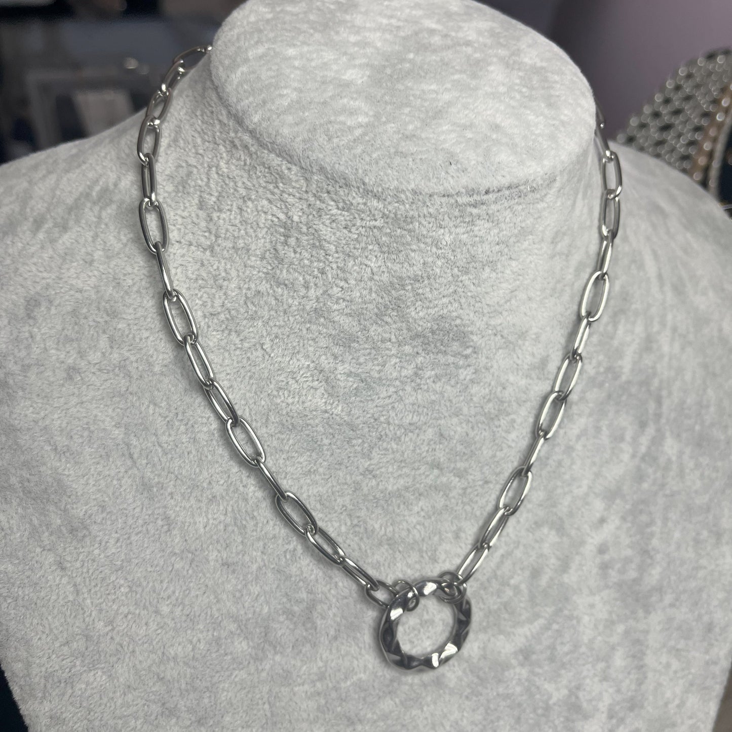 Collana Catena Cerchio in acciaio inox placcato argento con catena a maglie ovali e ciondolo cerchio, esposta su busto grigio