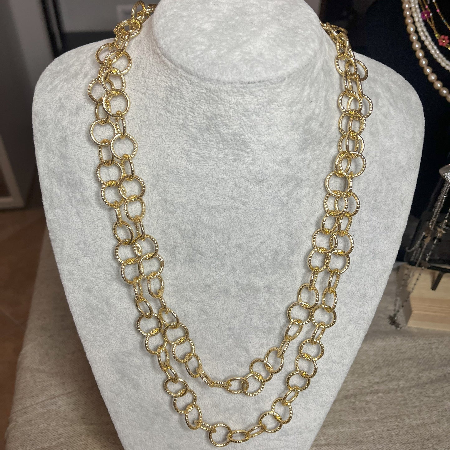 Collana elegante in alluminio placcato oro con doppia catena e cerchi intrecciati, esposta su busto bianco