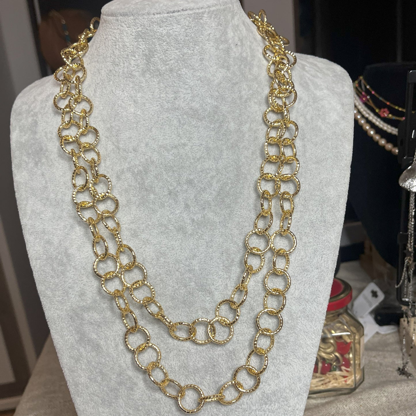 Collana elegante in alluminio placcato oro con doppia catena e cerchi intrecciati, esposta su busto bianco