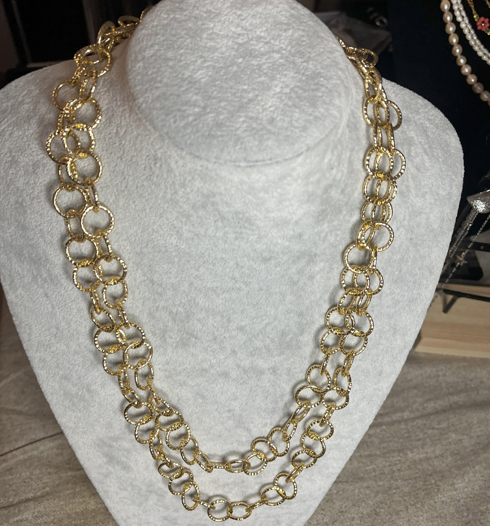 Collana elegante in alluminio placcato oro con doppia catena e cerchi intrecciati, esposta su busto bianco