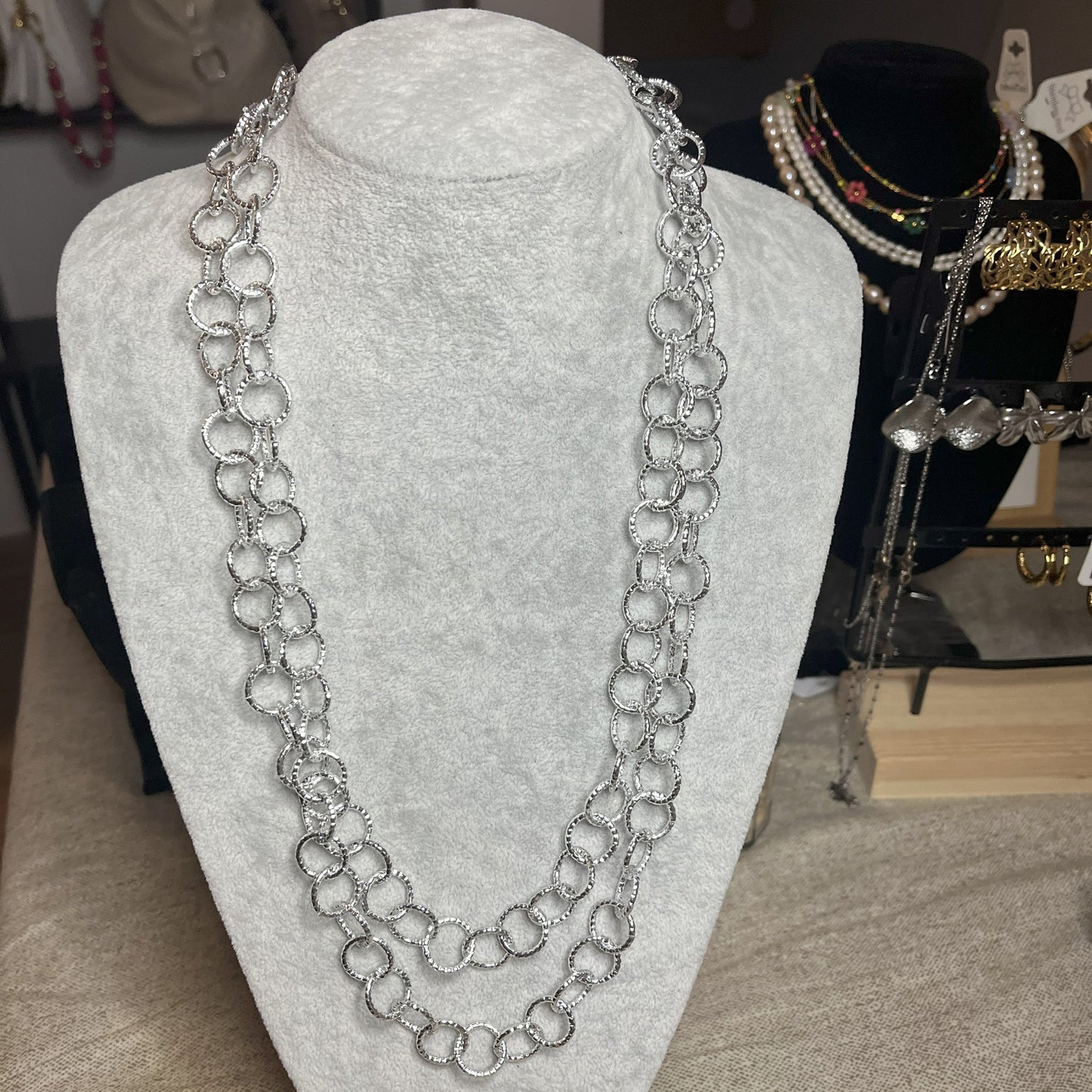 Collana elegante in alluminio placcato argento con doppia catena e cerchi intrecciati, esposta su busto bianco