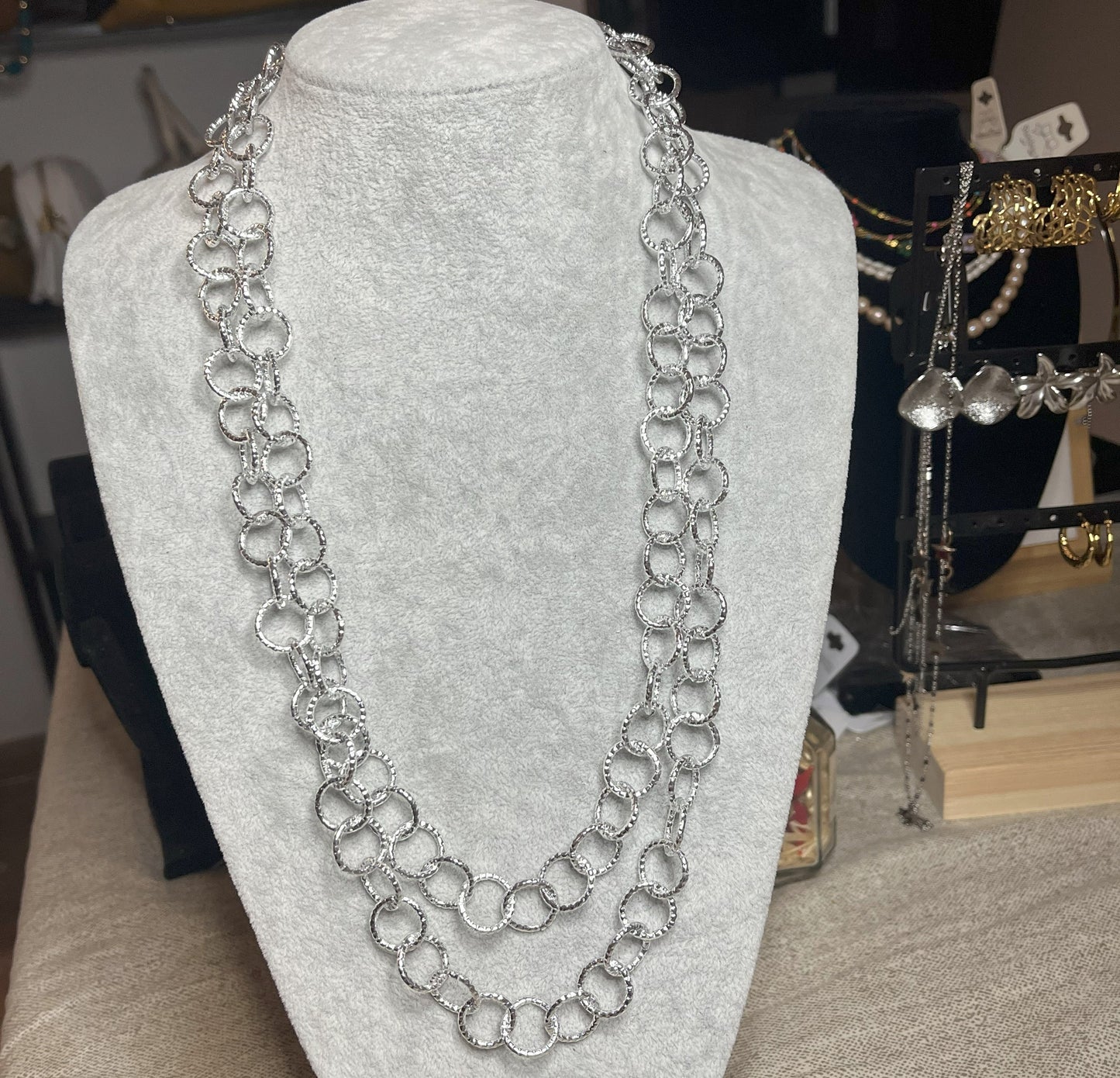 Collana elegante in alluminio placcato argento con doppia catena e cerchi intrecciati, esposta su busto bianco