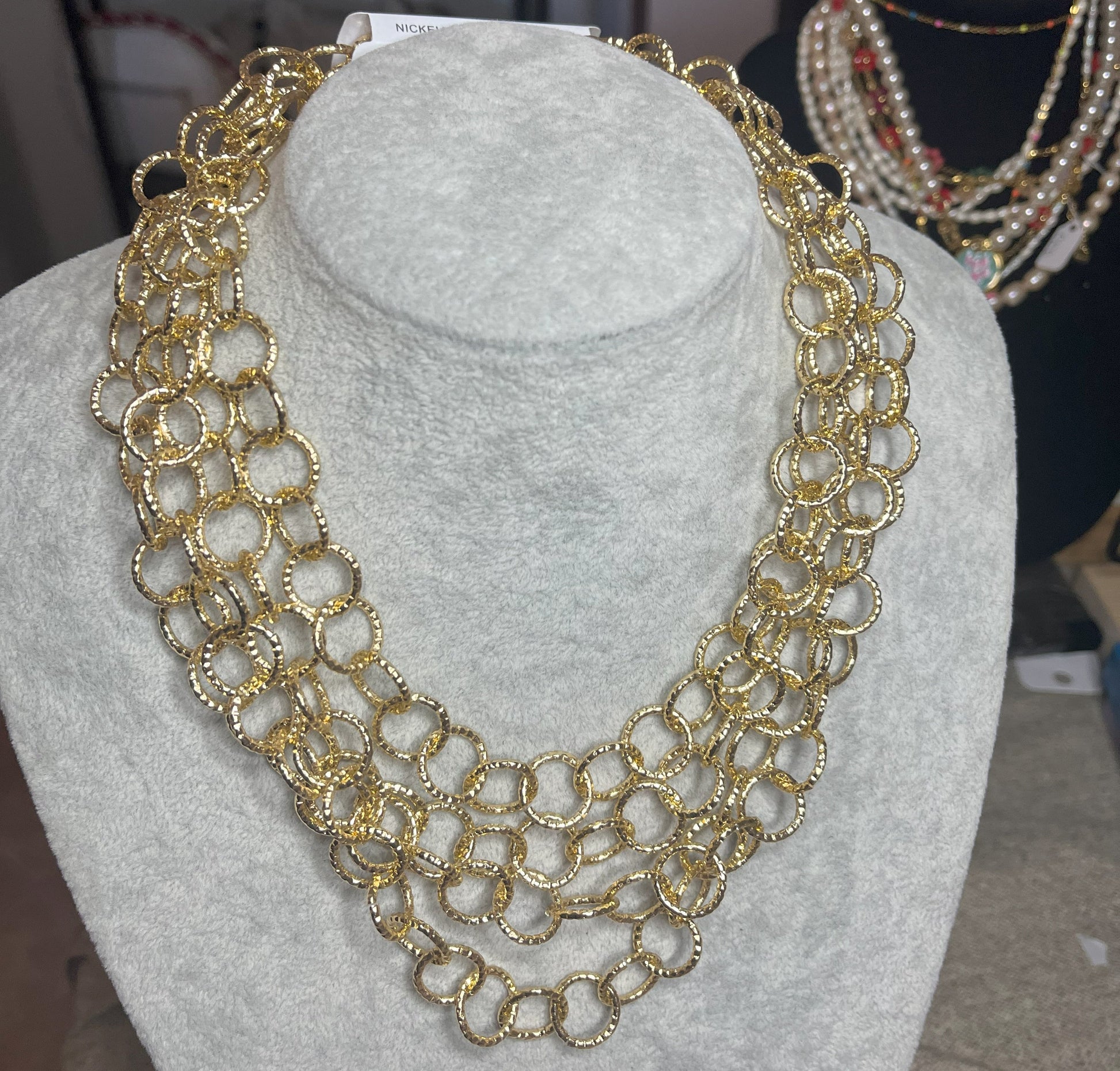 Collana elegante in alluminio placcato oro con quadrupla catena e cerchi intrecciati, esposta su busto bianco