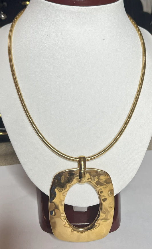 Collana Charlize in acciaio inossidabile placcato oro con catena a maglia serpente e pendente geometrico quadrato, esposta su busto bianco