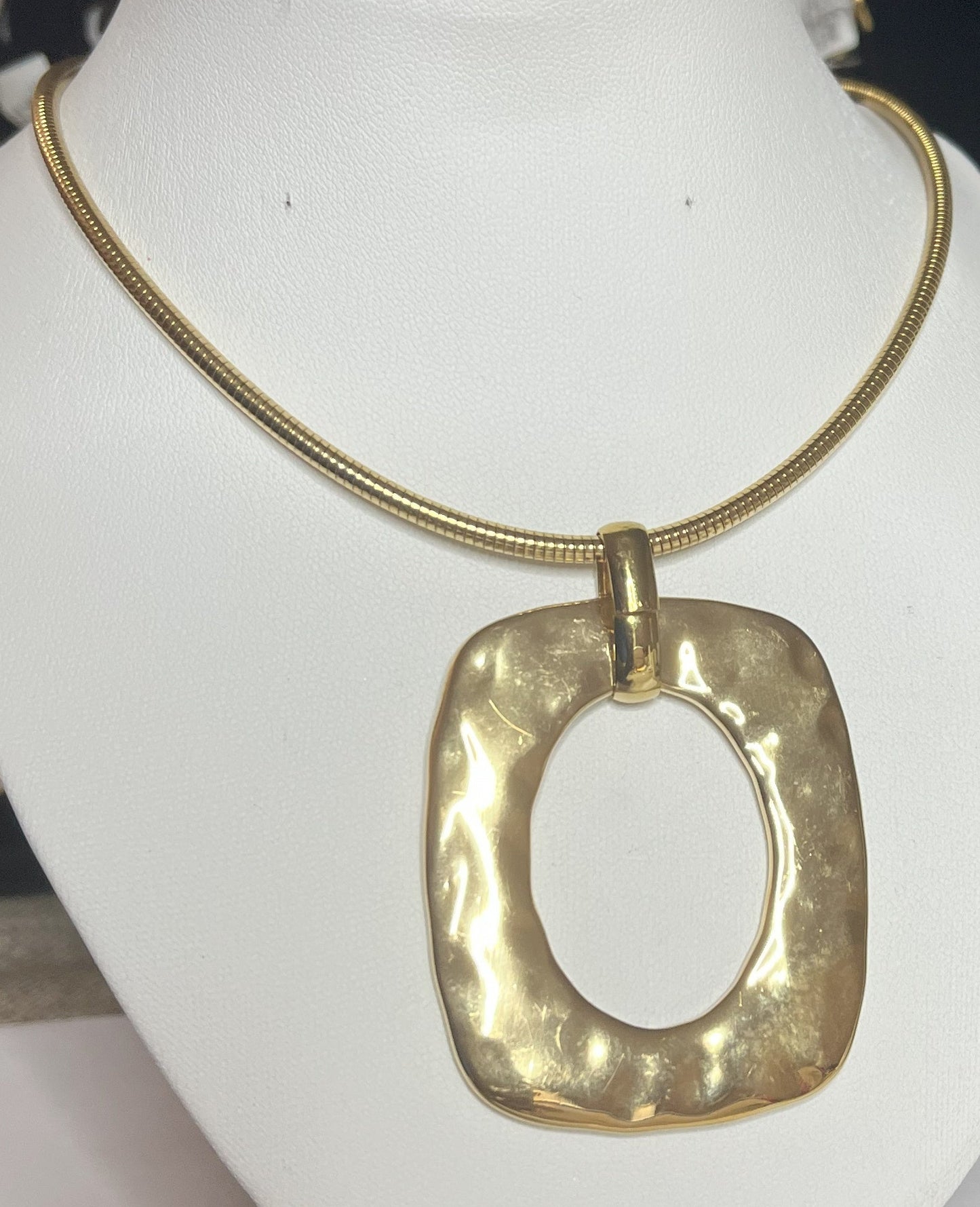 Collana Charlize in acciaio inossidabile placcato oro con catena a maglia serpente e pendente geometrico quadrato, esposta su busto bianco
